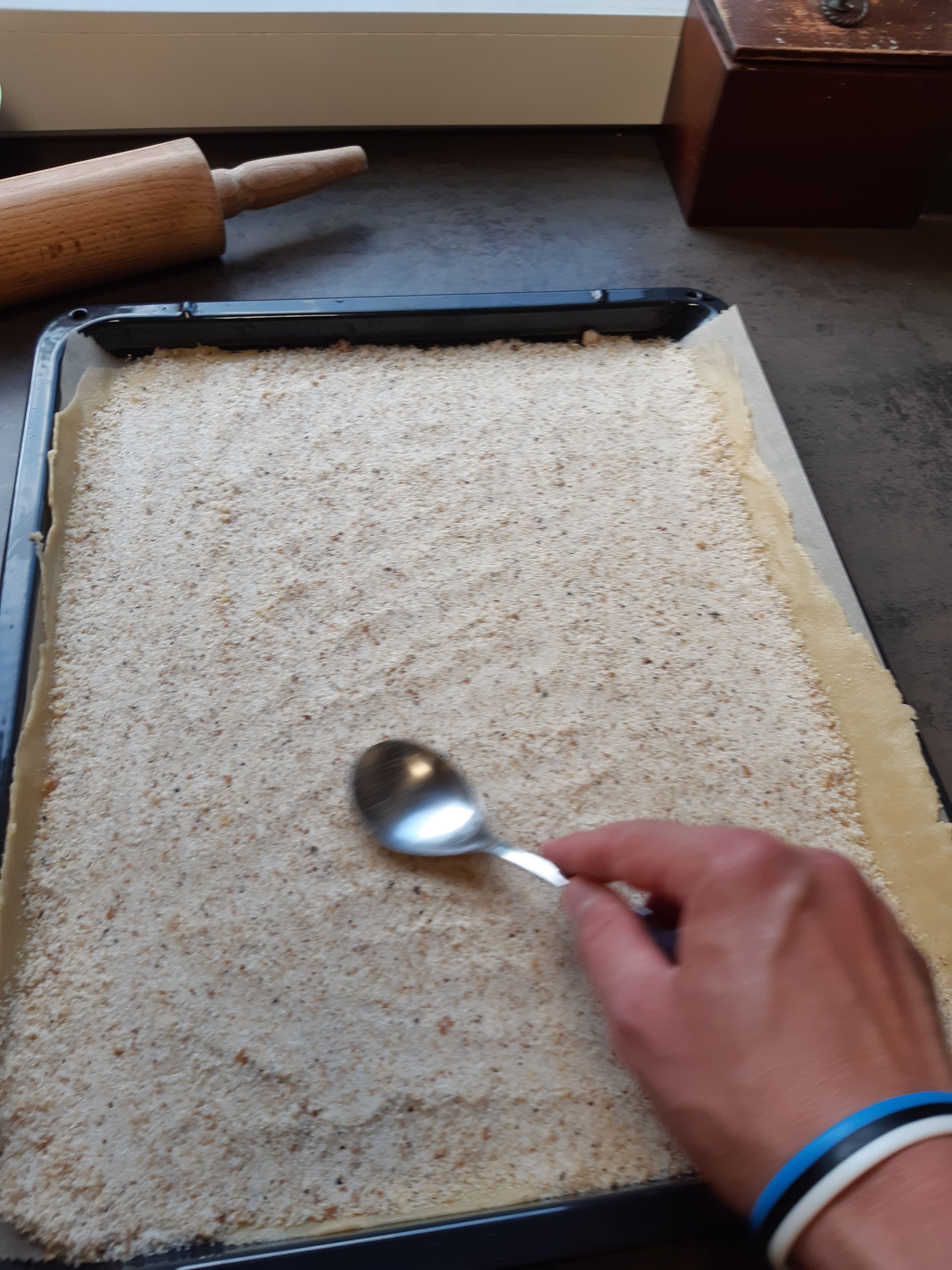 Ein Drittel der Füllung (Nuss-Zucker-Mischung) gleichmäßig auf dem Teig verteilen. 