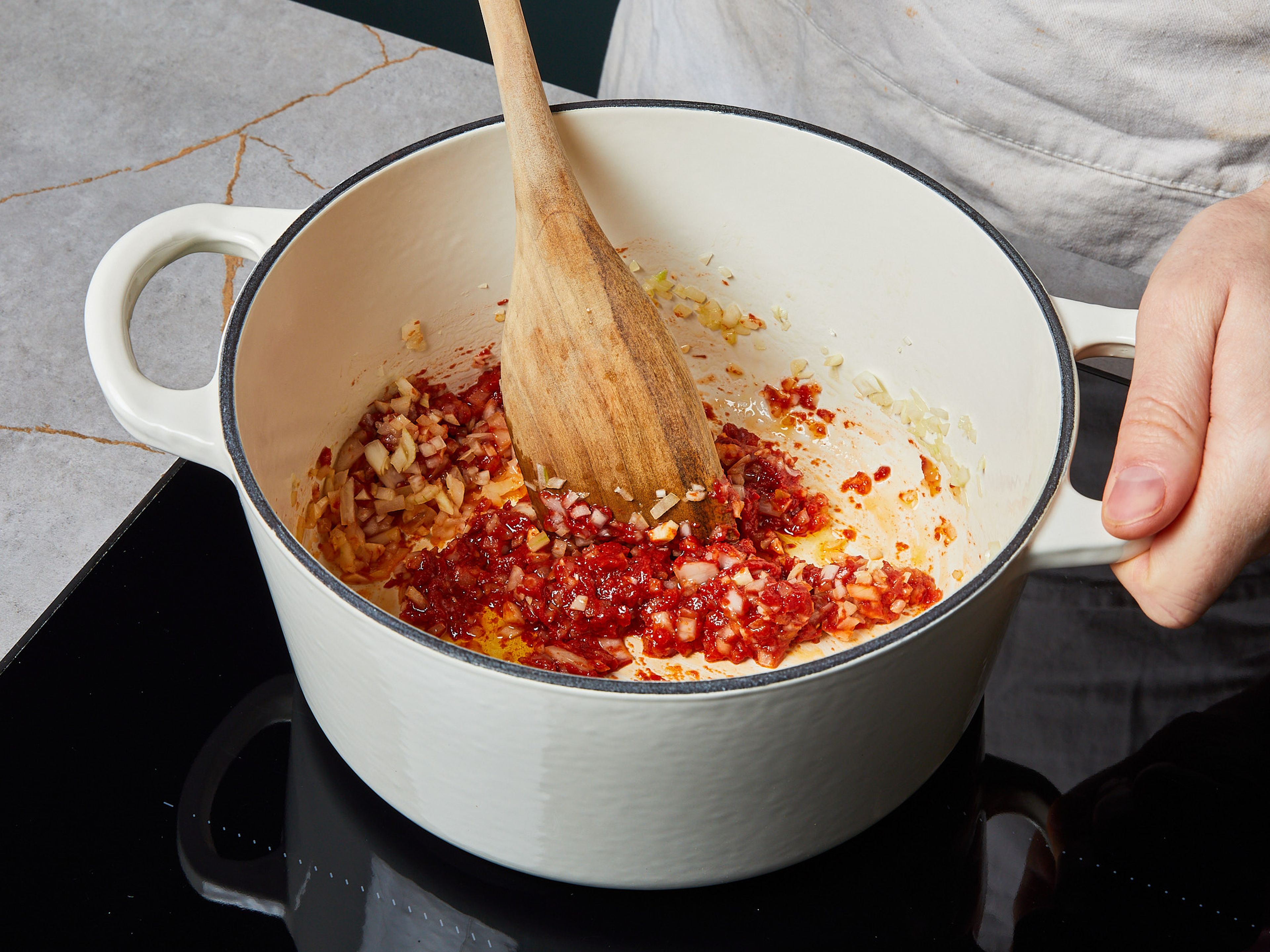 Stir in the tomato paste. Then, add the vegetable stock and crushed tomatoes.