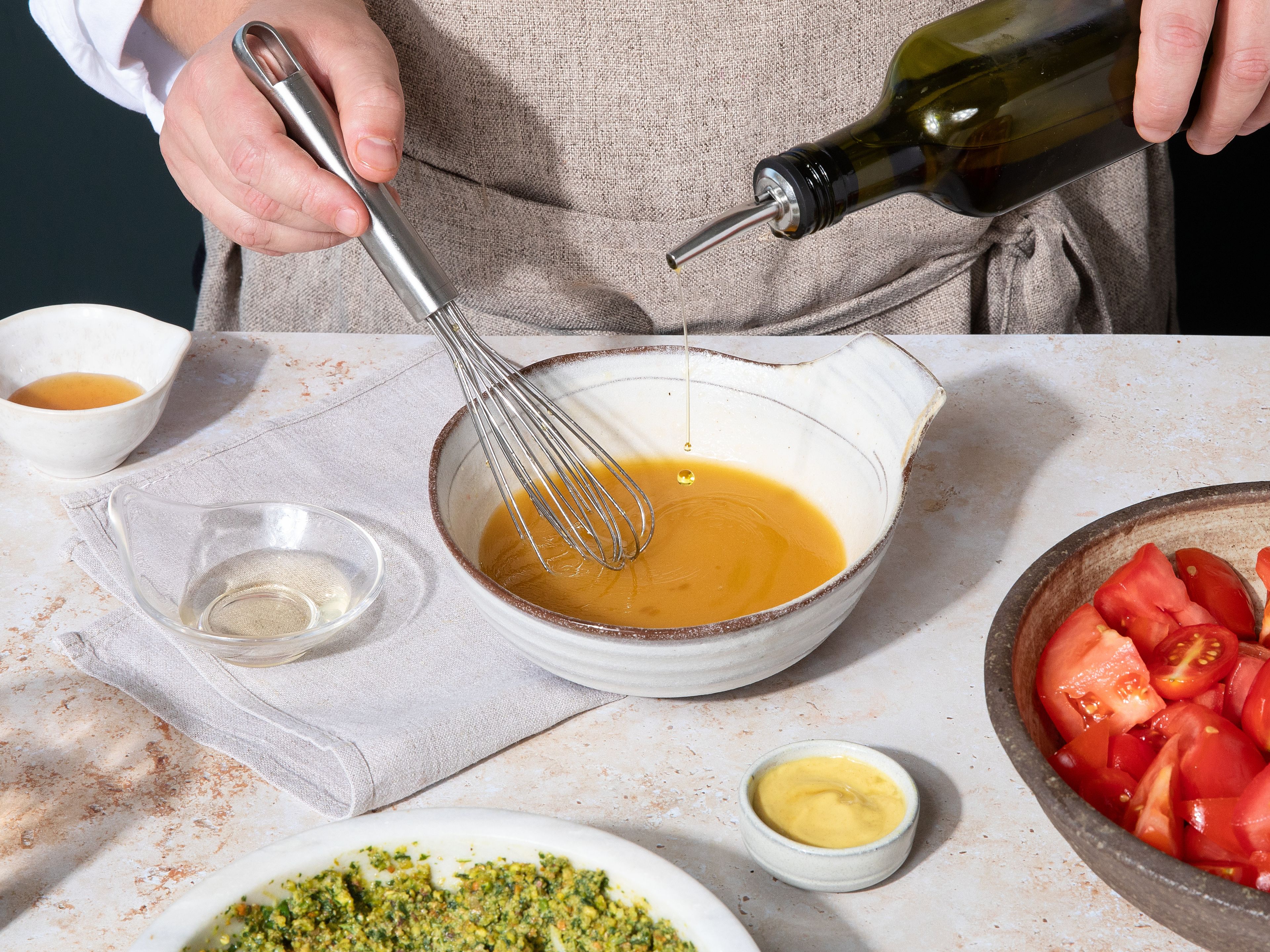 Wenn die Tomaten durchgezogen sind, durch ein Sieb geben und das ausgetretene Wasser in einer Schüssel auffangen. Honig, Balsamico und Dijon Senf dazugeben und unter stetigem Rühren langsam das restliche Olivenöl einlaufen lassen, bis ein cremiges Dressing entsteht.
