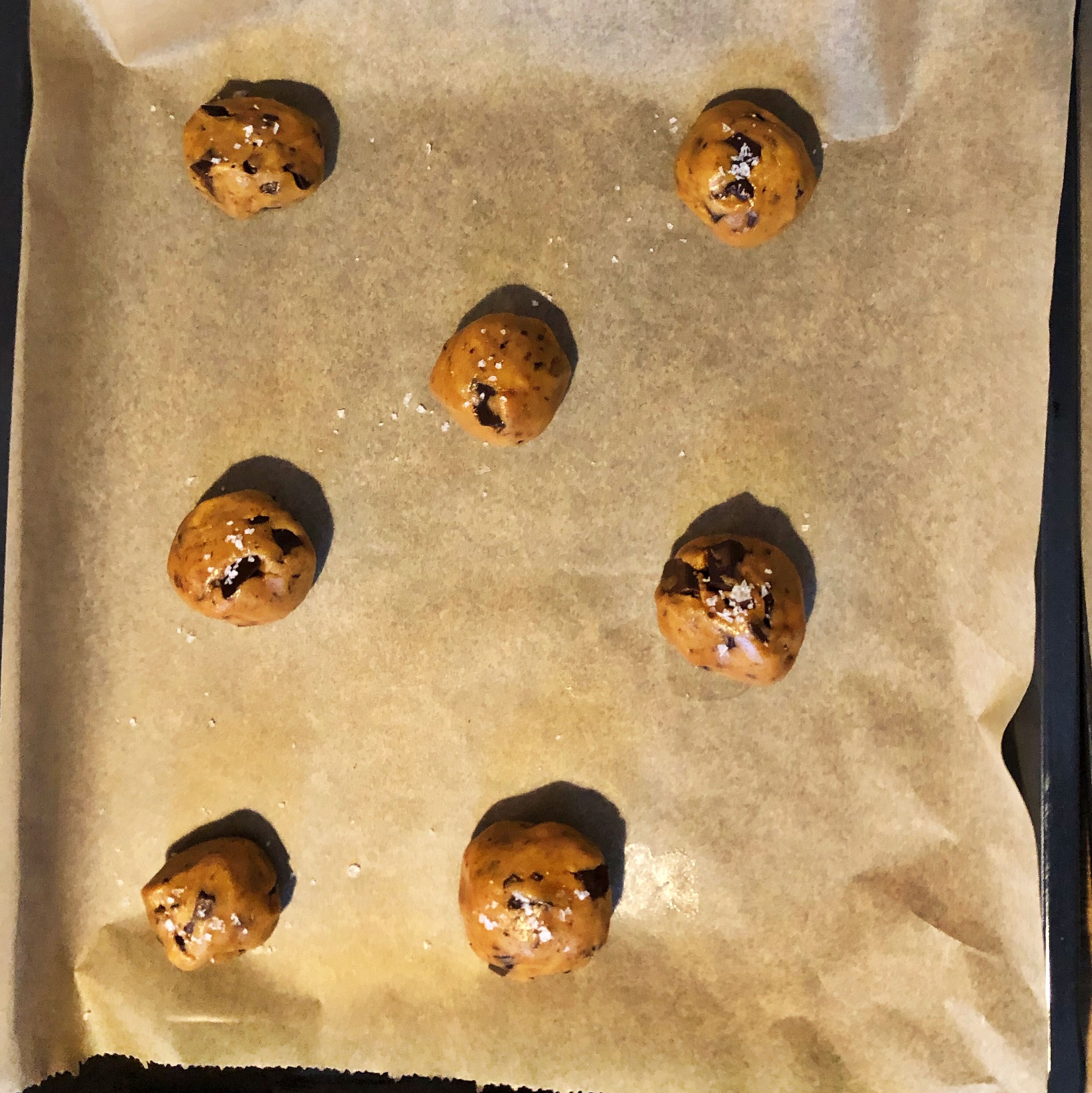 Roughly chop both chocolates, you should use one with 50% cacao, and one with 70% cacao. Fold chopped chocolate into the dough. Portion the dough into 12 equal-sized balls and transfer to two parchment-lined baking sheets. Sprinkle with flaky sea salt and bake for approx. 9 min.