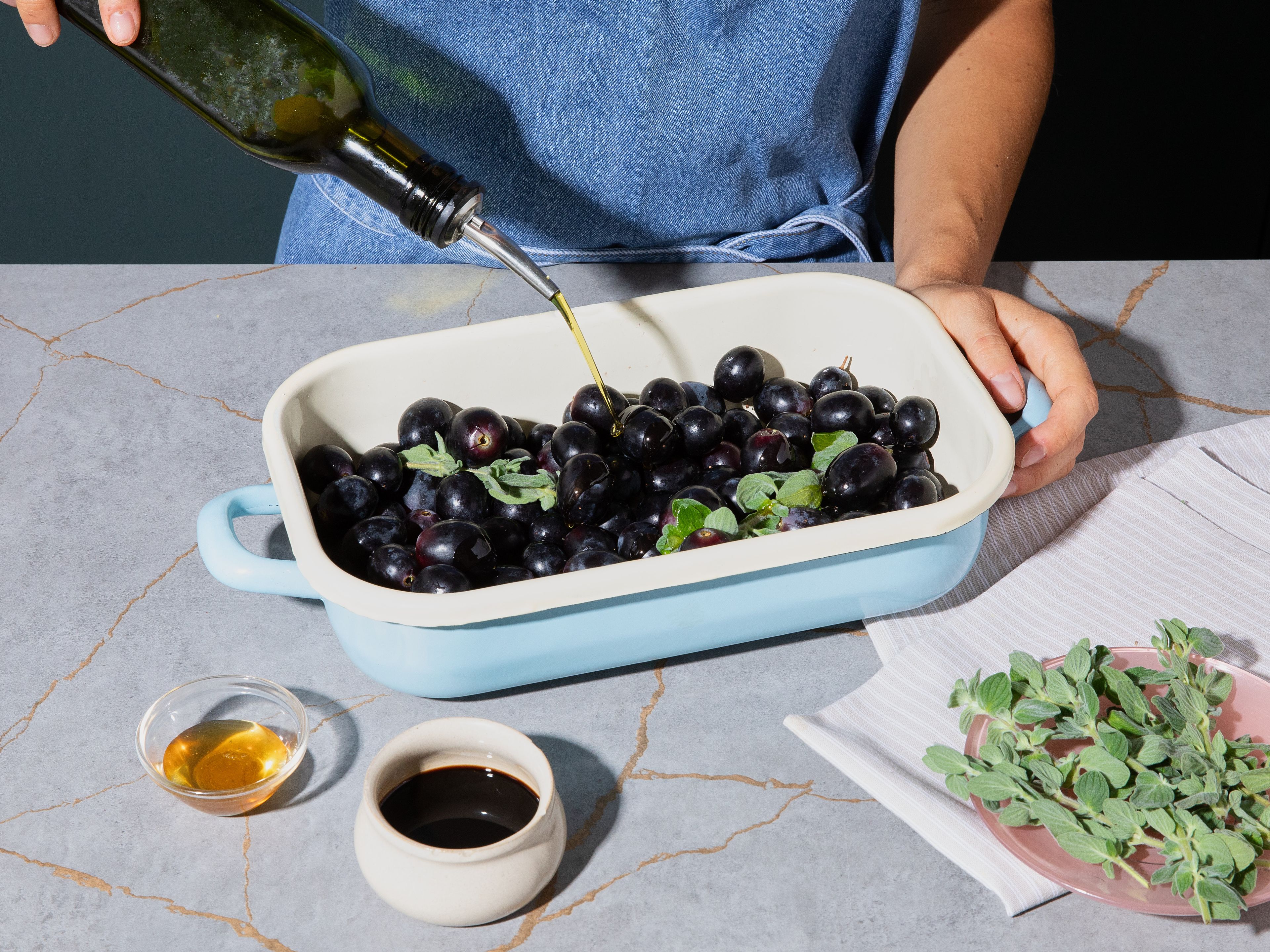 Add grapes to a baking dish. Add balsamic vinegar, honey, olive oil, and oregano, season with salt and pepper, and mix well. Roast in preheated oven for approx. 20–30 min. depending on size of grapes, until they develop dark spots and slightly burst.