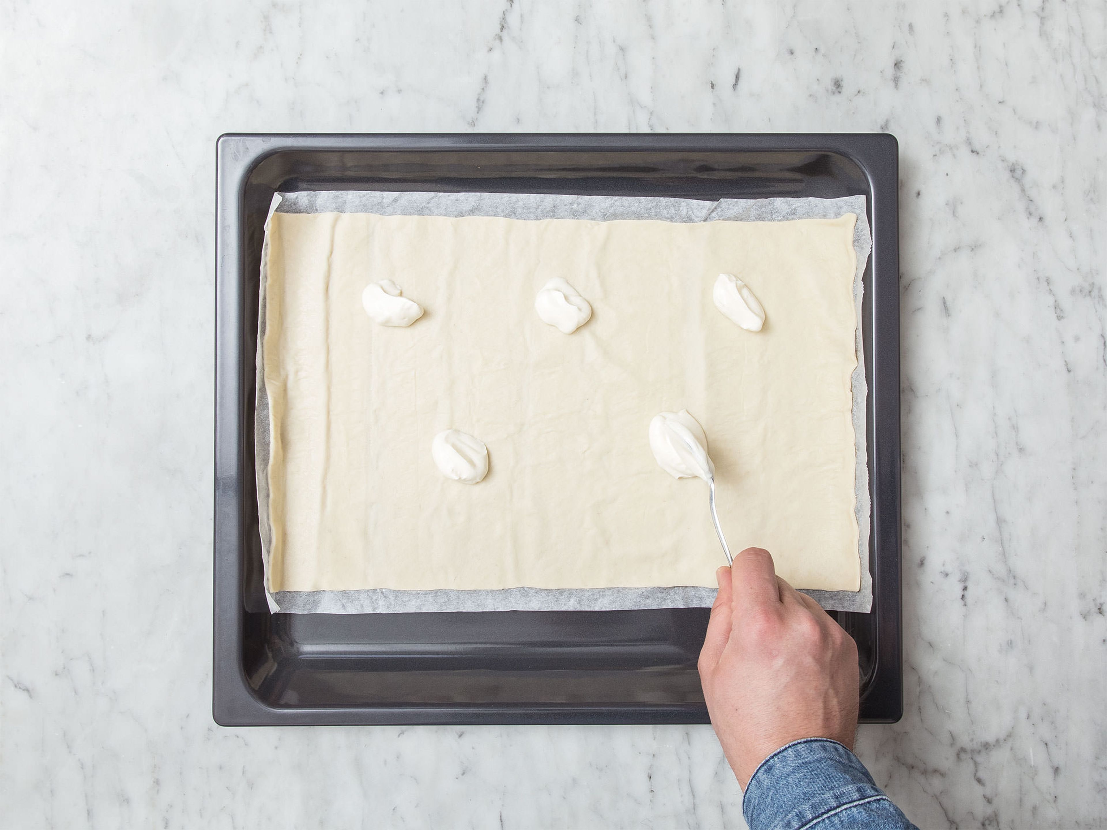 Preheat oven to 200°C/390°F. Transfer dough to a parchment-lined baking sheet. Spread sour cream in an even layer onto the dough.