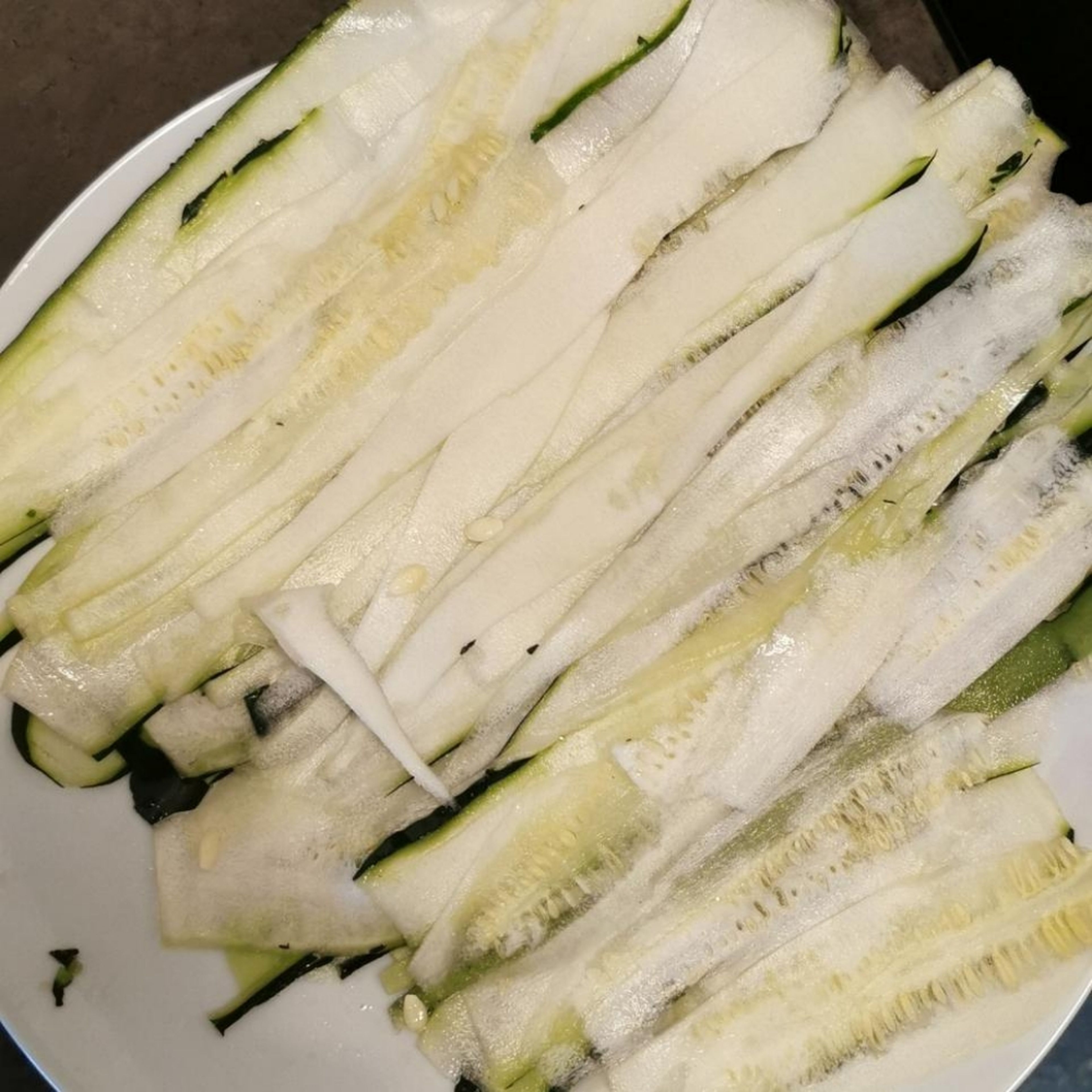 Zucchini mit einem Schäler in dünne Scheiben schneiden. Mit Salz bestreuen zum entwässern.
