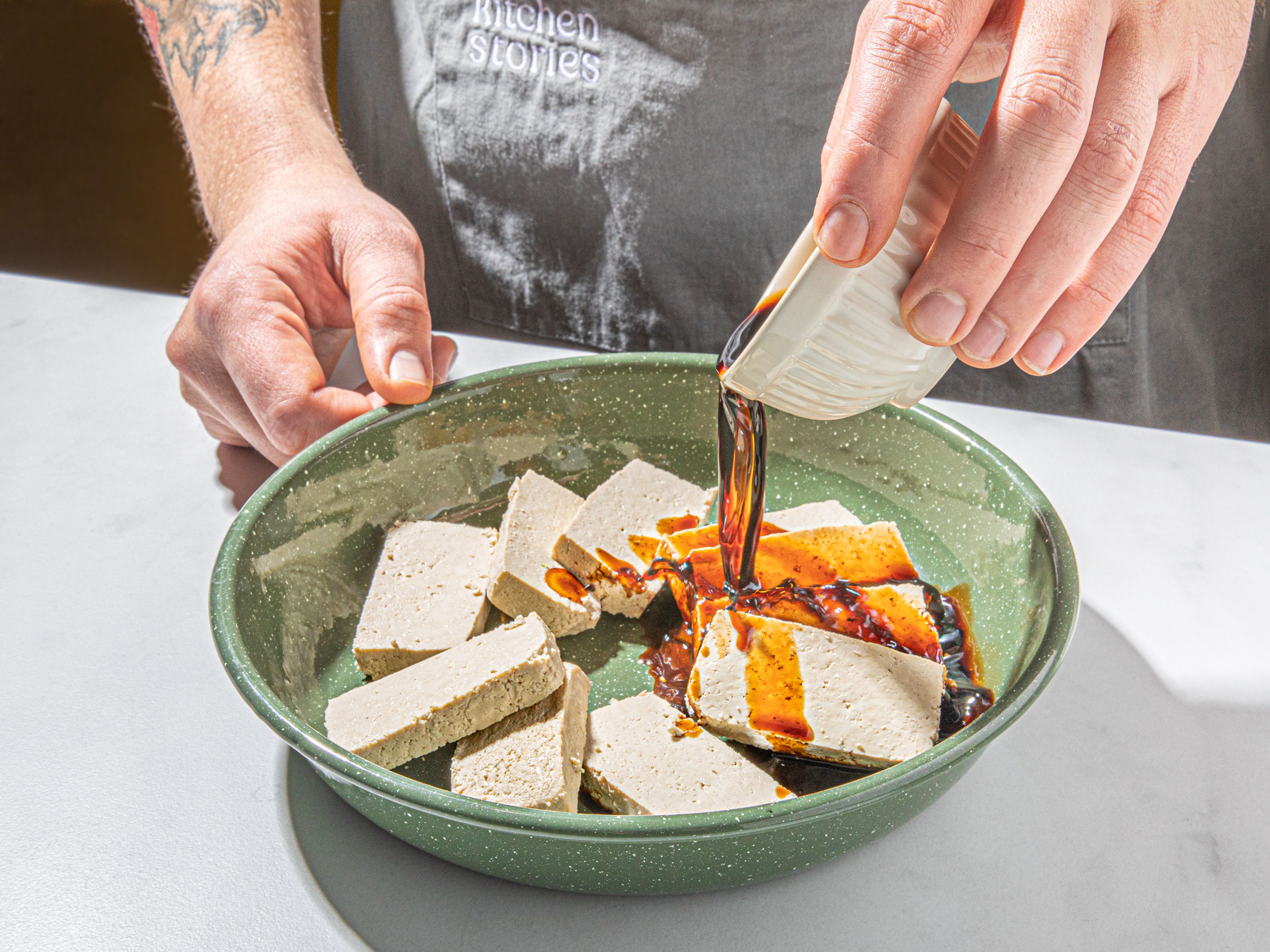 Tofu mit Küchenpapier trocken tupfen und in ca. 2 cm dicke Streifen schneiden. Balsamicoessig, Sojasauce und eine Prise Zucker in eine Schüssel geben und verquirlen. Den geschnittenen Tofu auf einen tiefen Teller legen und die Essig-Soja-Mischung darüber gießen. Mit Frischhaltefolie abdecken, in den Kühlschrank stellen und mindestens 30 Min. oder bis zu 8 Std. marinieren lassen.