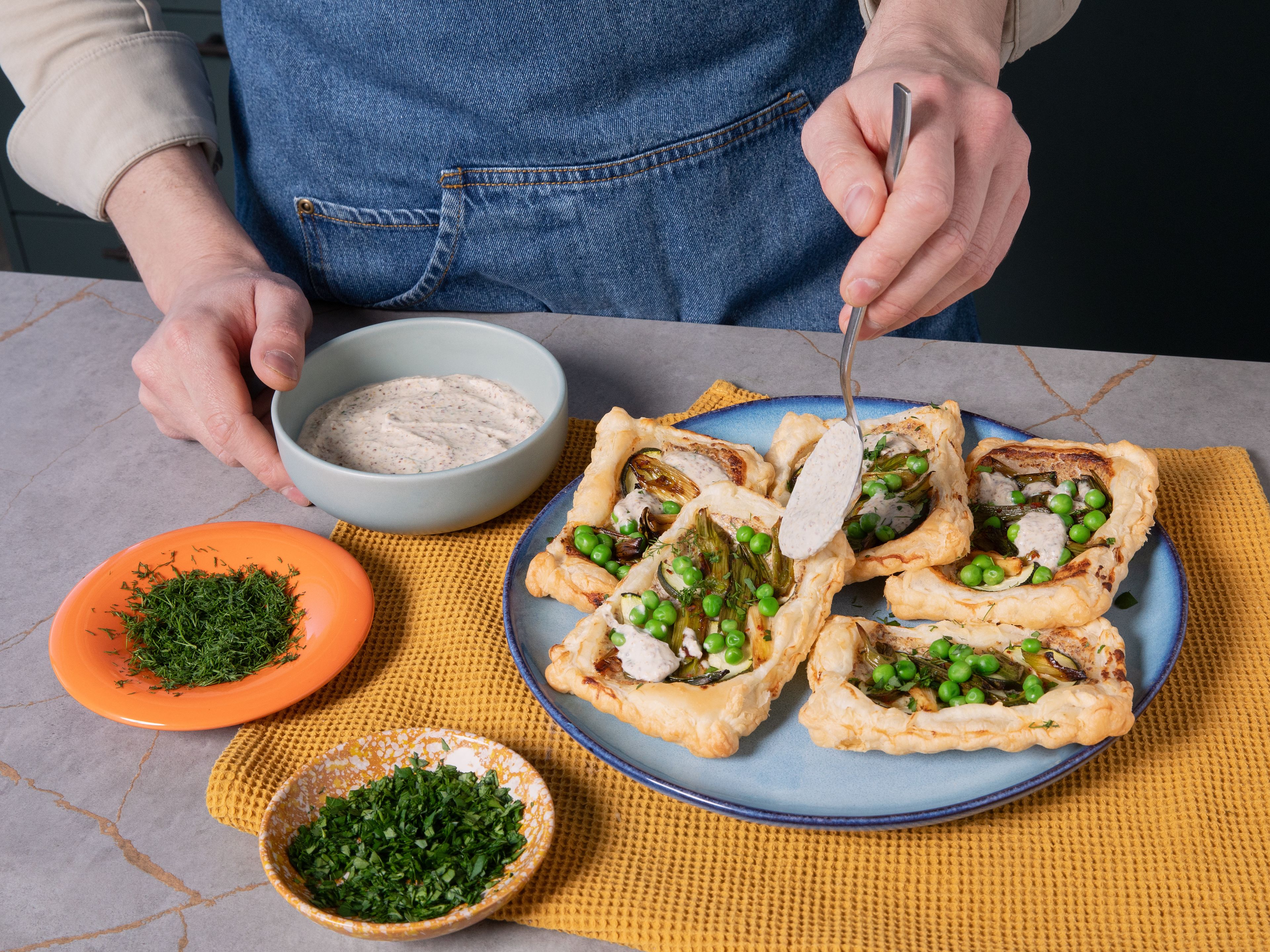 Nach Ende der Backzeit die Erbsen auf jede Mini-Tarte geben und weitere ca. 3–5 Min. backen. Fertige Mini-Tarts kurz auskühlen lassen und mit restlicher Frischhain Natur Creme sowie Petersilie und restlichem Dill toppen.