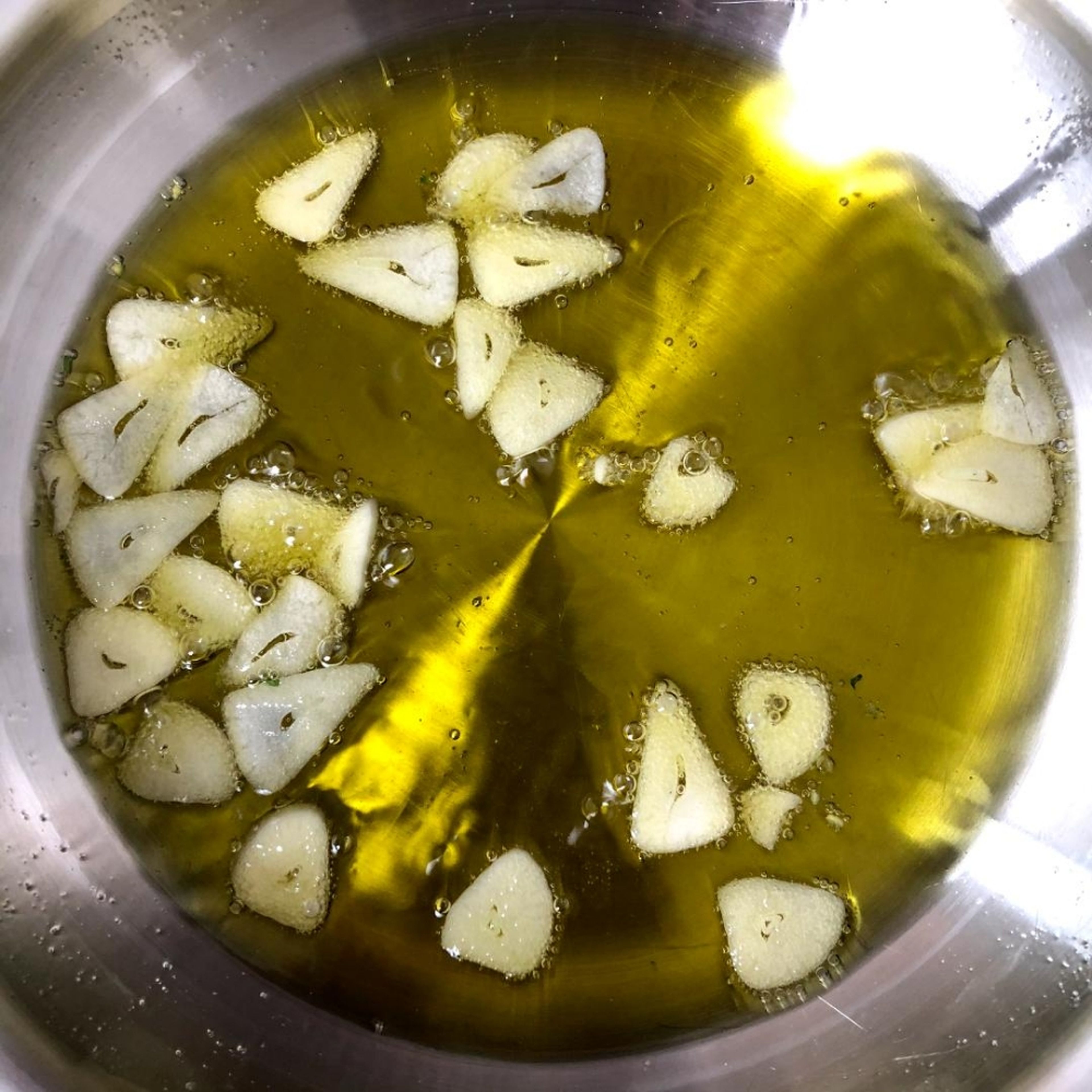 Pour 120 ml of olive oil in a small pan and add the garlic slices. Now slowly heat the oil to medium heat. Once the oil is hot and the garlic is roasted, add the parsley, lemon zest and salt to it. (Be careful, it will splatter a little.) Immediately after, remove the pan from the heat, as the gremolata is ready.