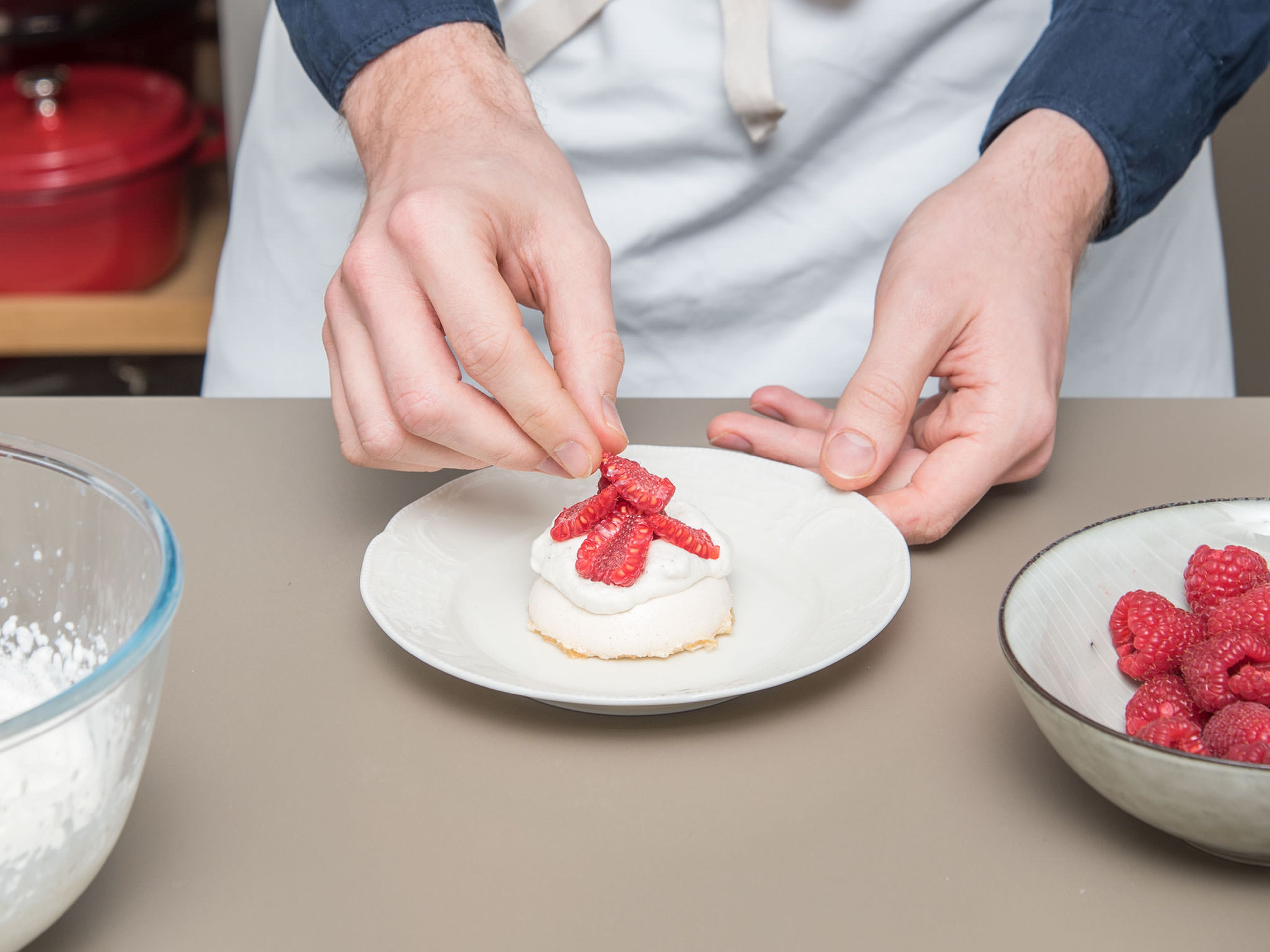 Top the Pavlovas with vanilla cream and garnish with halved raspberries. Enjoy!