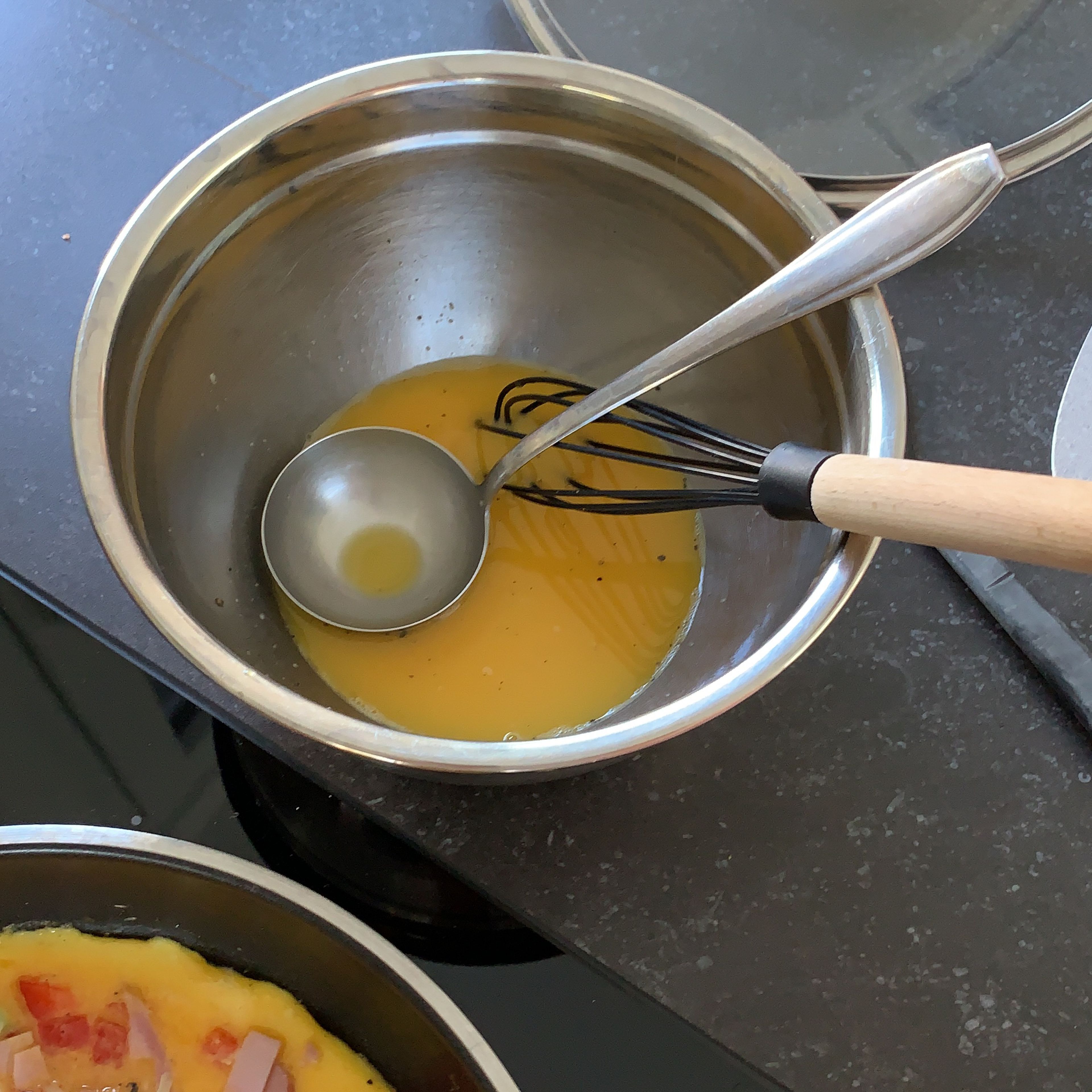 Die Eier-Mischung in die Pfanne geben und durch Schwenken verteilen. Die restlichen Zutaten in der Pfanne verteilen, den Käse zum Schluss verstreuen.