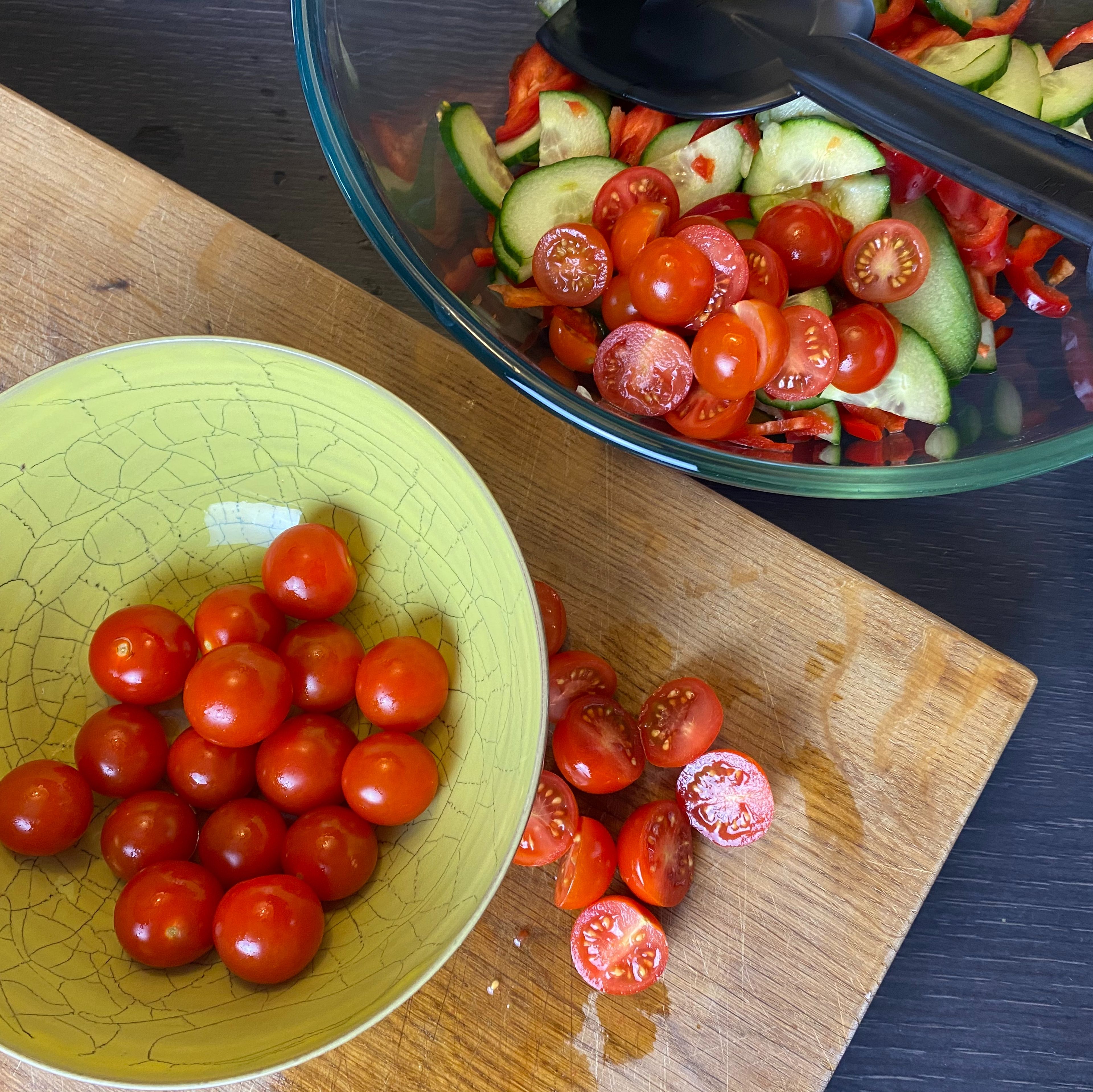 Während die Kichererbsen braten, werden die gewaschenen Tomaten gehälftet und zu Gurke und Spitzpaprika gegeben.