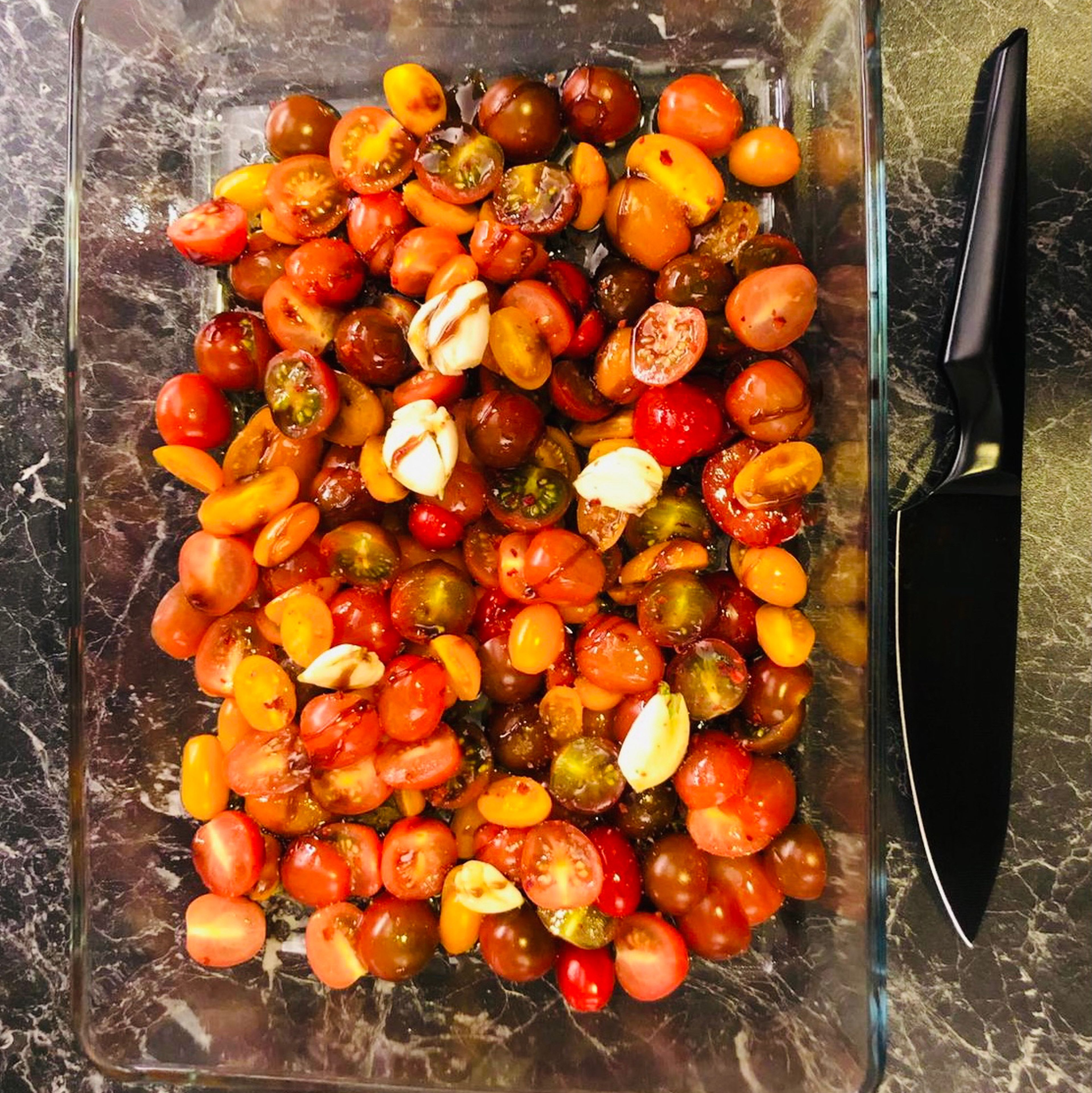 Preheat the oven to 180 degrees C fan. Cut the tomatoes in half, peel the garlic and crush them with the side of the knife. Then place them all together in the oven dish. Spoon 1/2 (50 ml) of the oliveoil, the sugar beet syrup, the chili flakes and 1/2 teaspoon of salt on the tomatoe-garlic mix. Note: You can easily use 1/2 tablespoon sugar or honey instead of the sugar beet syrup.
