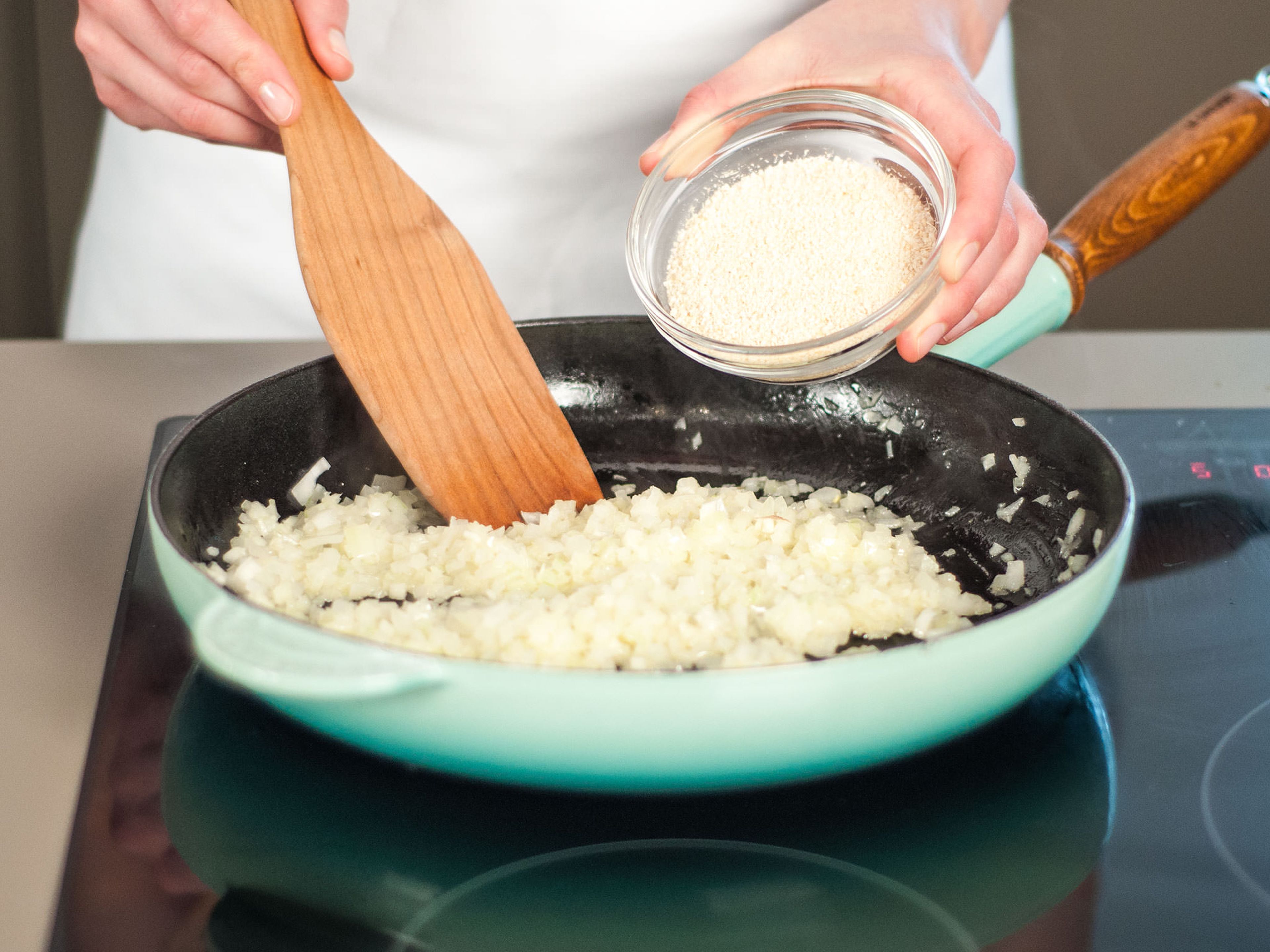 Ein Drittel der Butter in eine Pfanne geben. Zwiebeln und Knoblauch hinzufügen und ca. 3 – 4 Min. bei mittlerer Hitze glasig anbraten. Dann geröstetes Maniokmehl hinzugeben und gut verrühren. Für weitere 1 – 2 Min. kochen lassen.