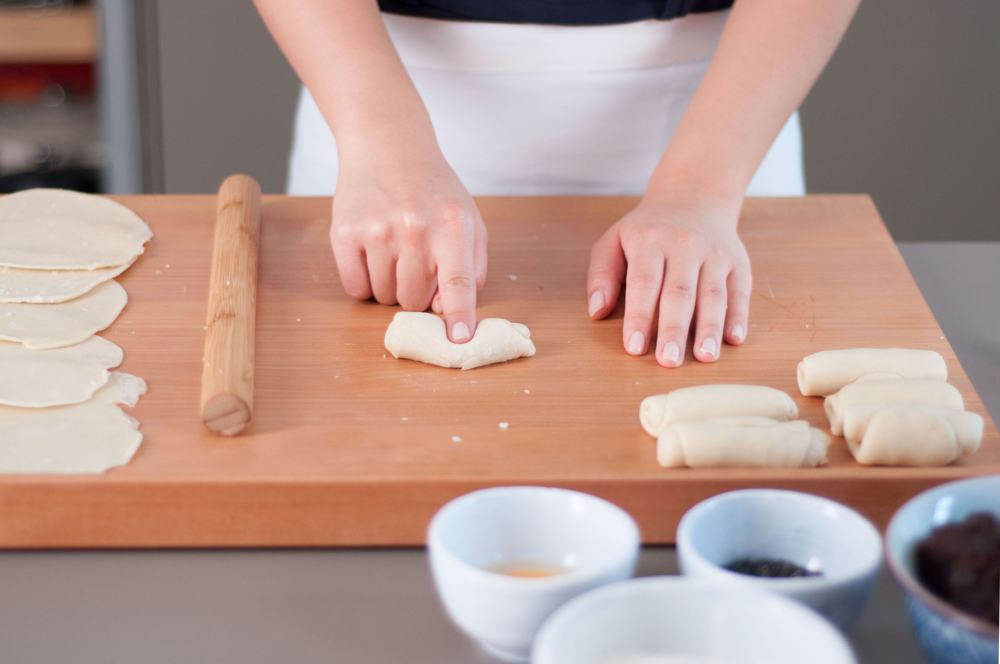 Make an indentation in the center of each roll with your finger. Wrap the dough into a circle with the indentation at its center. Shape into a smooth ball and roll this ball into a thin, round disc.