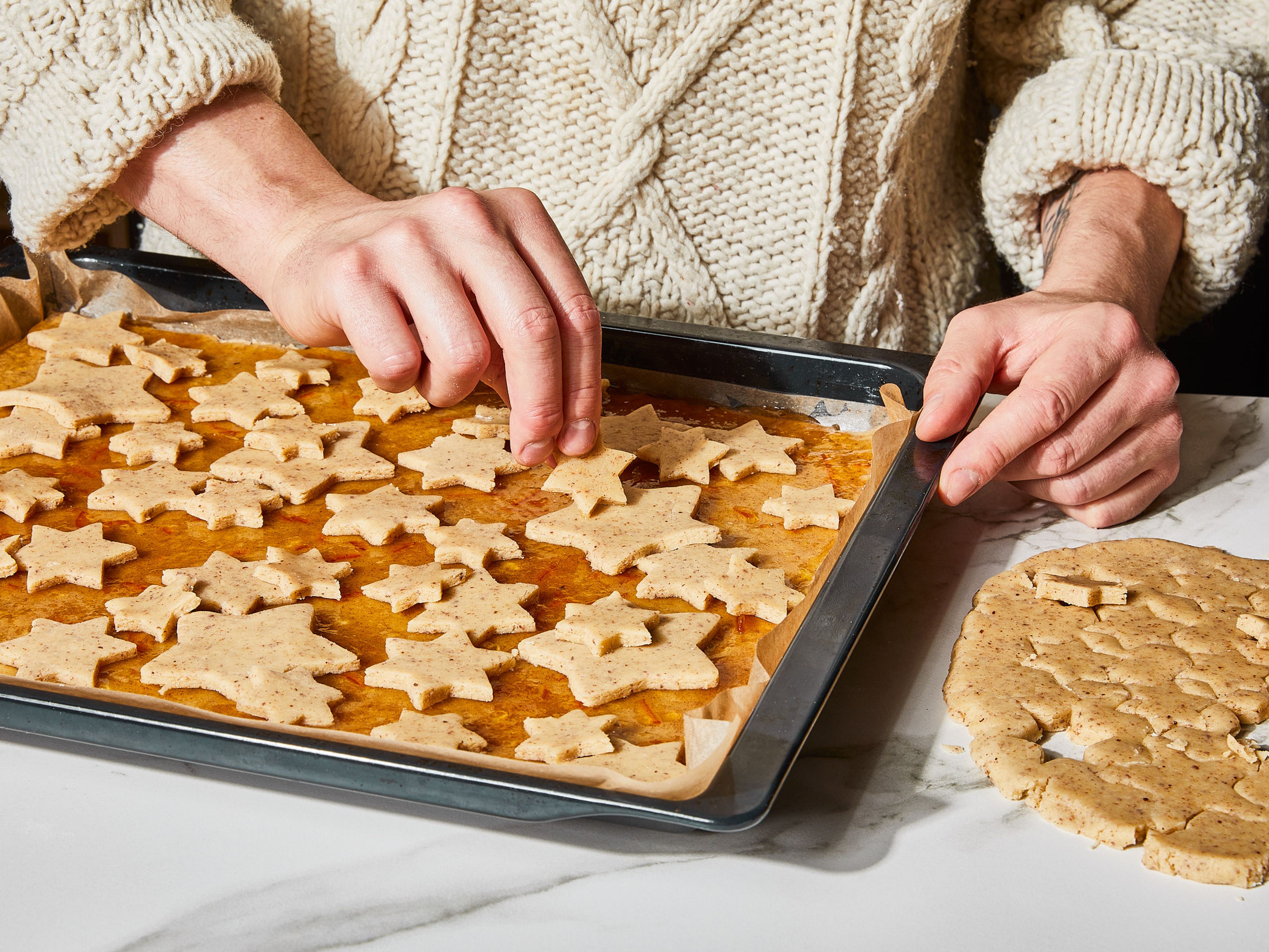 Den restlichen Teig ca. 0,5 cm dick ausrollen und Sterne in verschiedenen Größen ausstechen. Die Marmeladenoberfläche nach Belieben mit den ausgestochenen Sternen belegen. Im vorgeheizten Ofen ca. 30 Minuten backen, bis die Sterne an den Rändern leicht gebräunt sind.