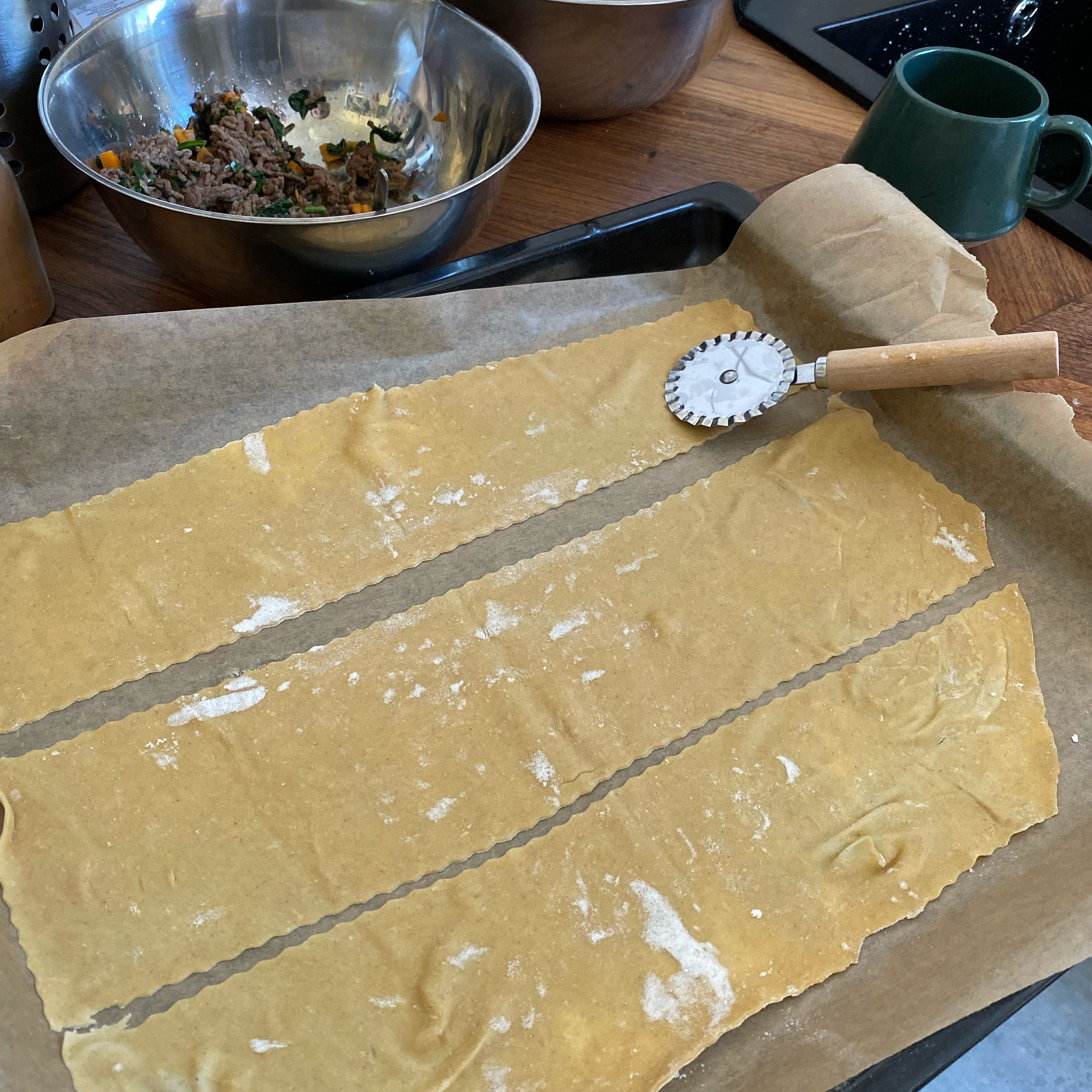 Pastateig zu einem Rechteck ausrollen und in 3 Streifen schneiden.