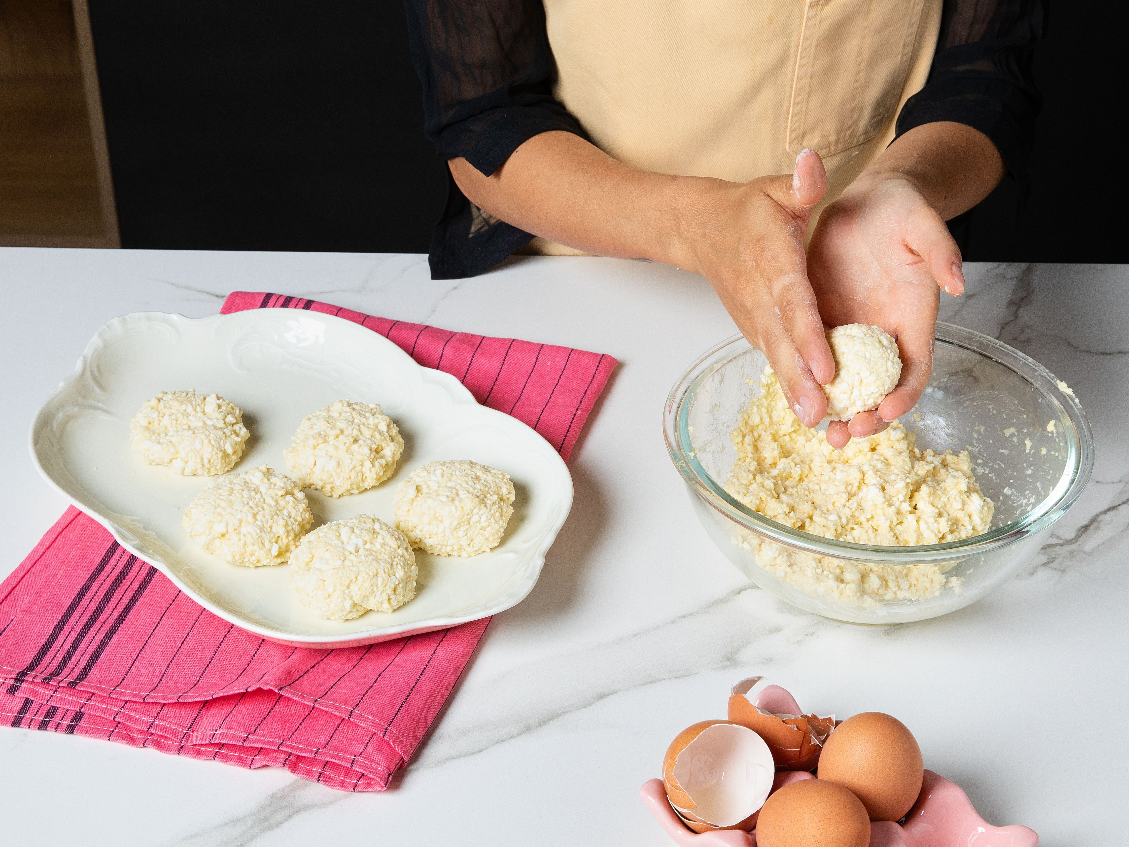 In a bowl, mash the tvorog cheese with a fork until smooth. Add eggs, flour, sugar, vanilla extract and a salt, then mix until a very soft, but moldable, sticky dough forms. Shape into even balls and gently flatten them to form small, thick pancakes.