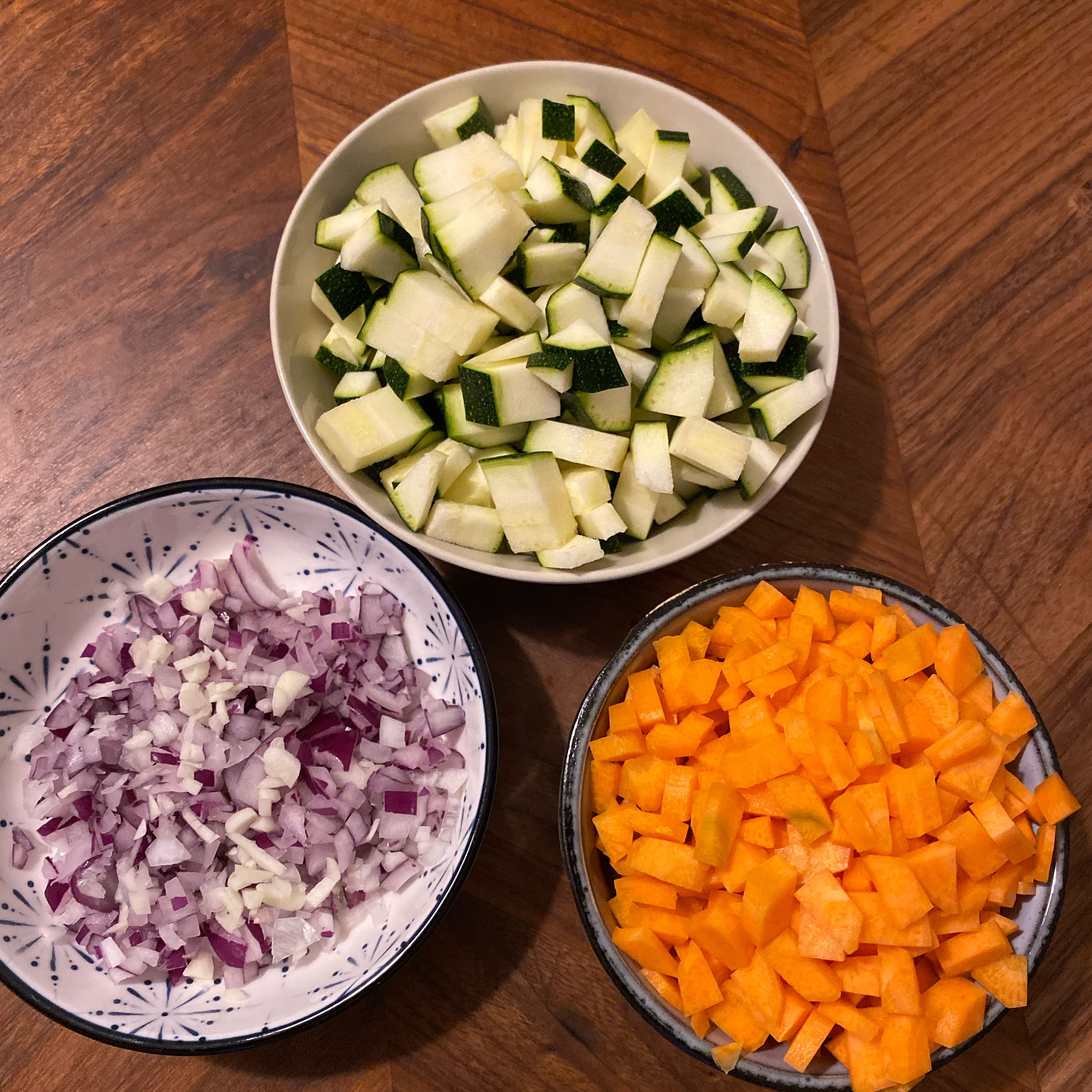 Knoblauch, Zwiebel, Karotten und Zucchini in Würfel schneiden, die Kidneybohnen und den Mais abgießen.