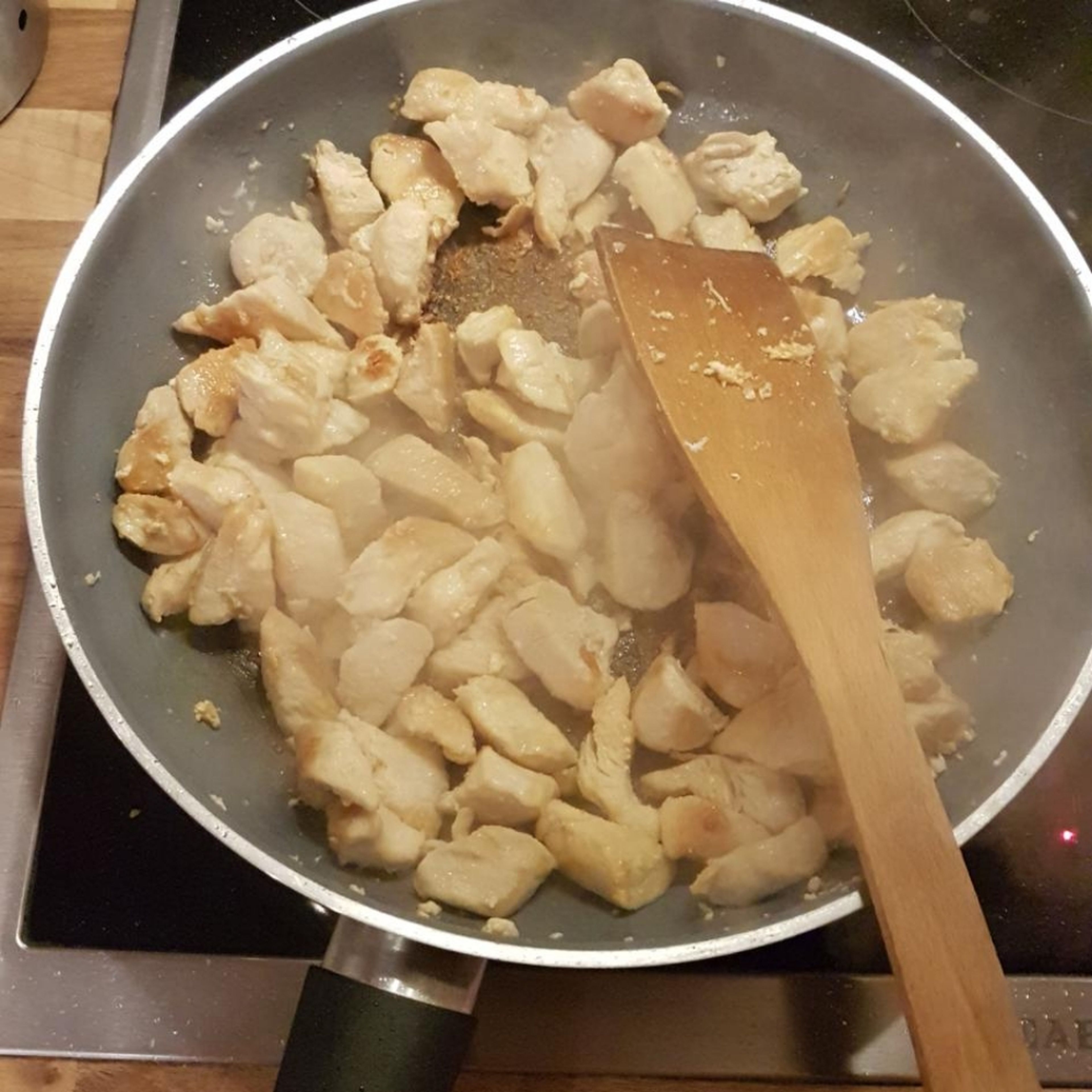 angebratenes Fleisch aus Pfanne nehmen und Zwiebeln und Knoblauch in Olivenöl anschwitzen