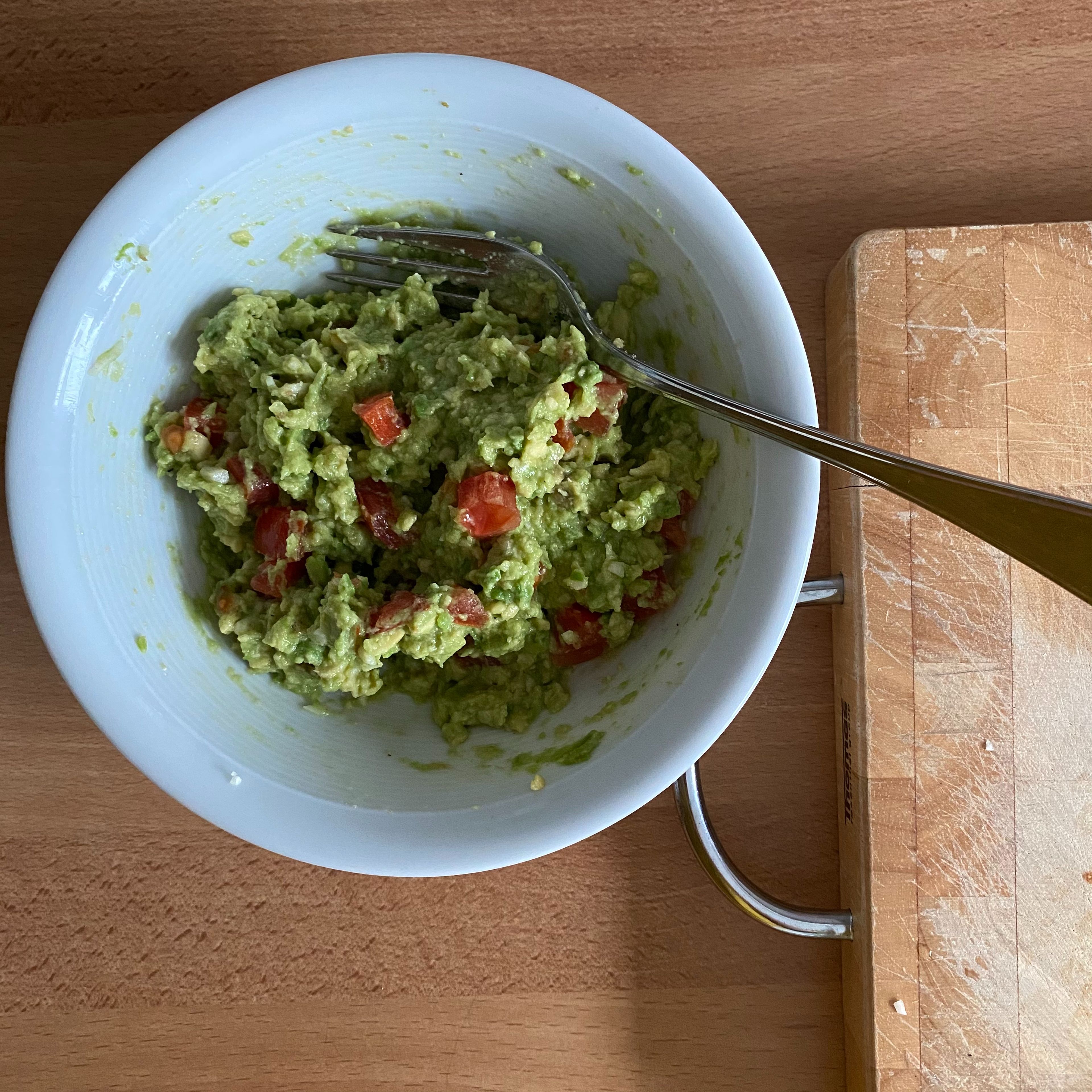 Die Enden der Tomate in kleine Würfel schneiden. Diese zusammen mit dem Knoblauch und dem Limettensaft zu der Avocado geben und vermengen und mit Salz und Pfeffer abschmecken.