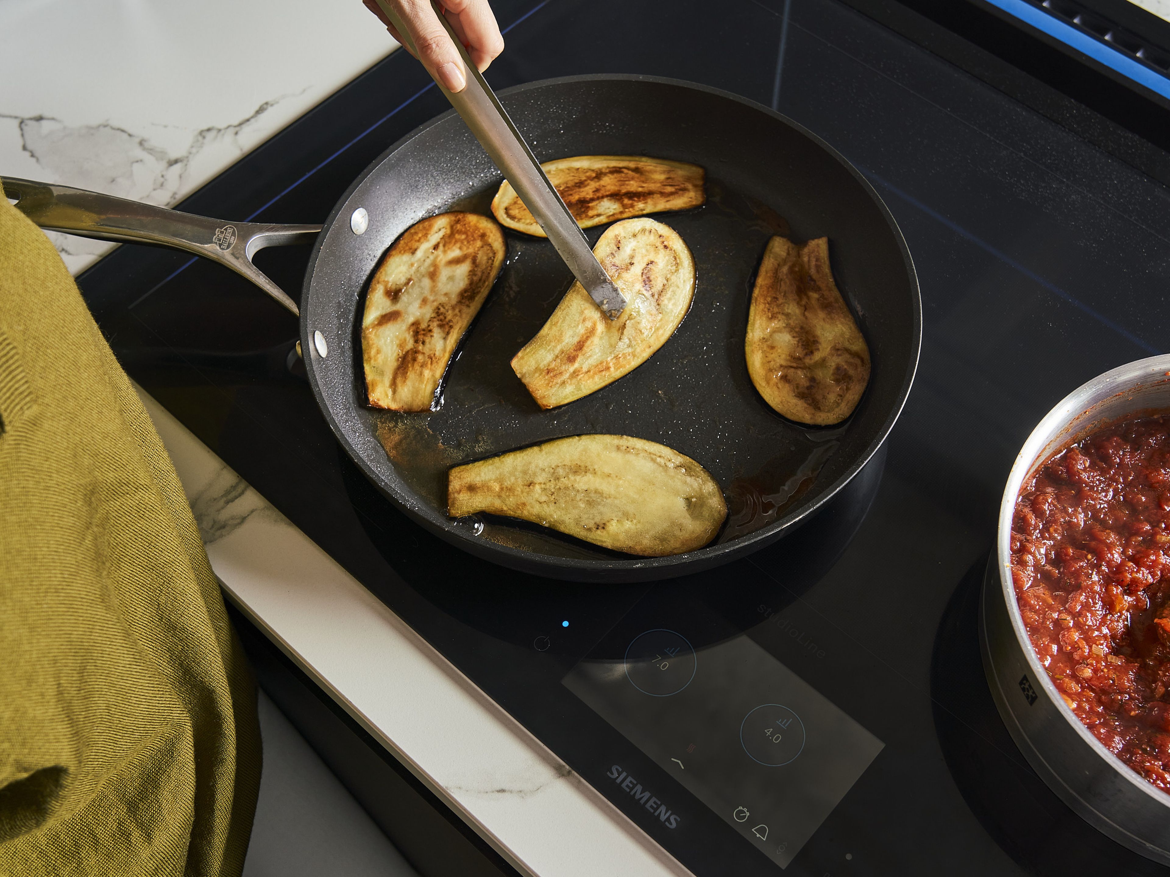 Meanwhile, add a generous amount of olive oil to a frying pan and heat over medium heat. Pat the aubergine slices dry, then dredge in flour, shake off any excess and fry for approx. 2–3 min. per side until golden brown. Leave to drain on paper towels and set aside.