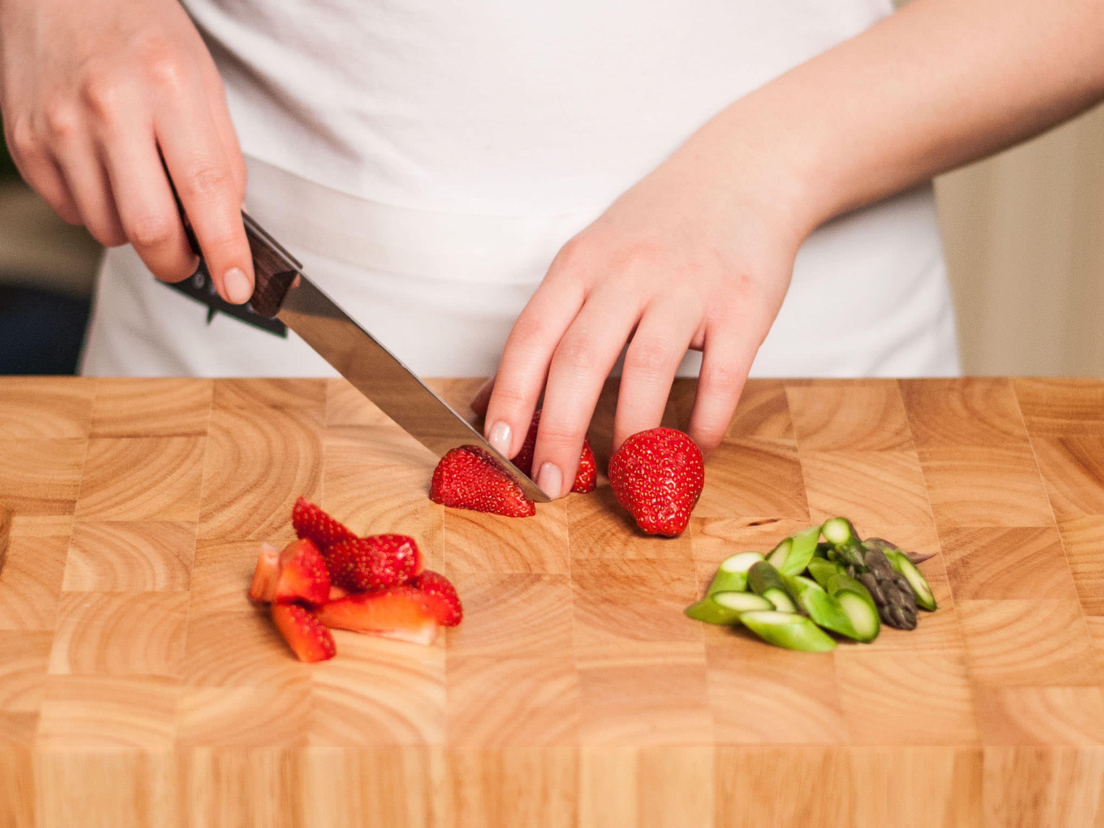 Die holzigen Enden vom Spargel abschneiden und nach Belieben leicht schräg in Stücke schneiden (ca. 1 cm lang). Erdbeeren vom Strunk befreien und vierteln.