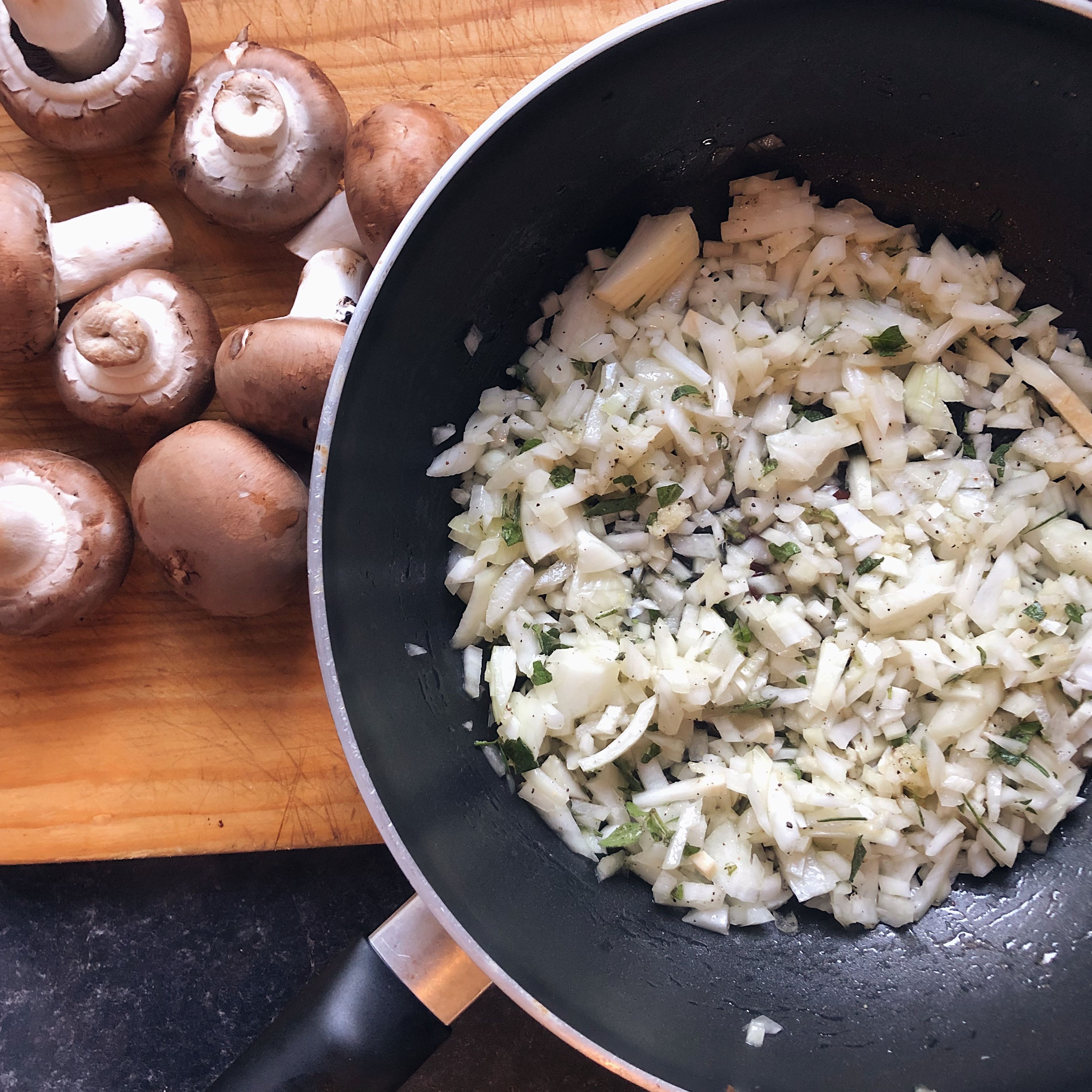 Dice onion, press garlic, finely chop fresh herbs and add salt and pepper to the pan. Pour on a good amount of olive oil and sweat on a medium heat for 10 minutes.