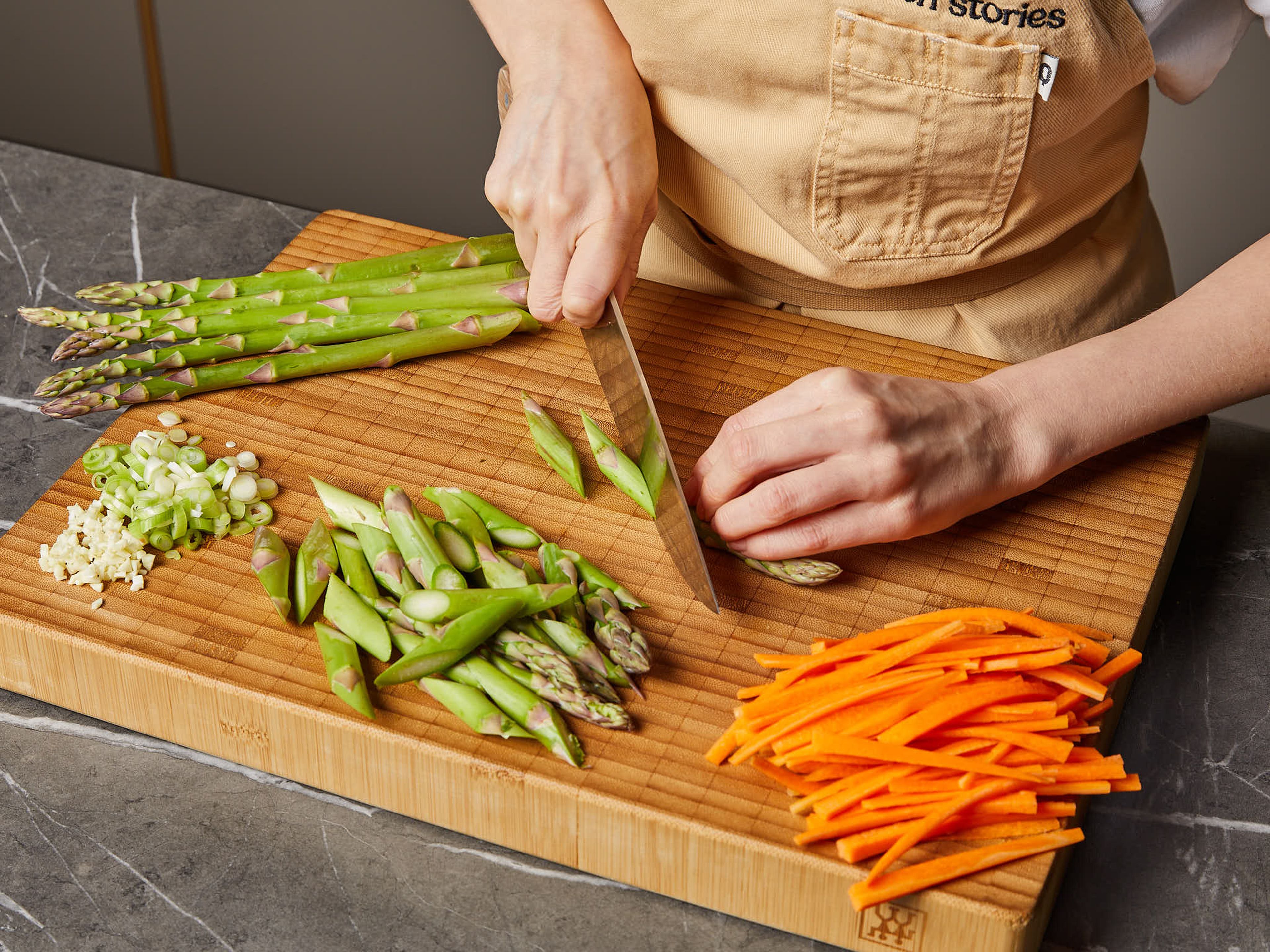 Cut off the woody bottoms of the asparagus and cut the remaining pieces diagonally into bite sized pieces. Peel the carrot and cut into thin strips. Finely chop the garlic. Slice the white part of the scallion to fine rings and set aside the green part, thinly slicing them for garnishing. Juice the lemon.