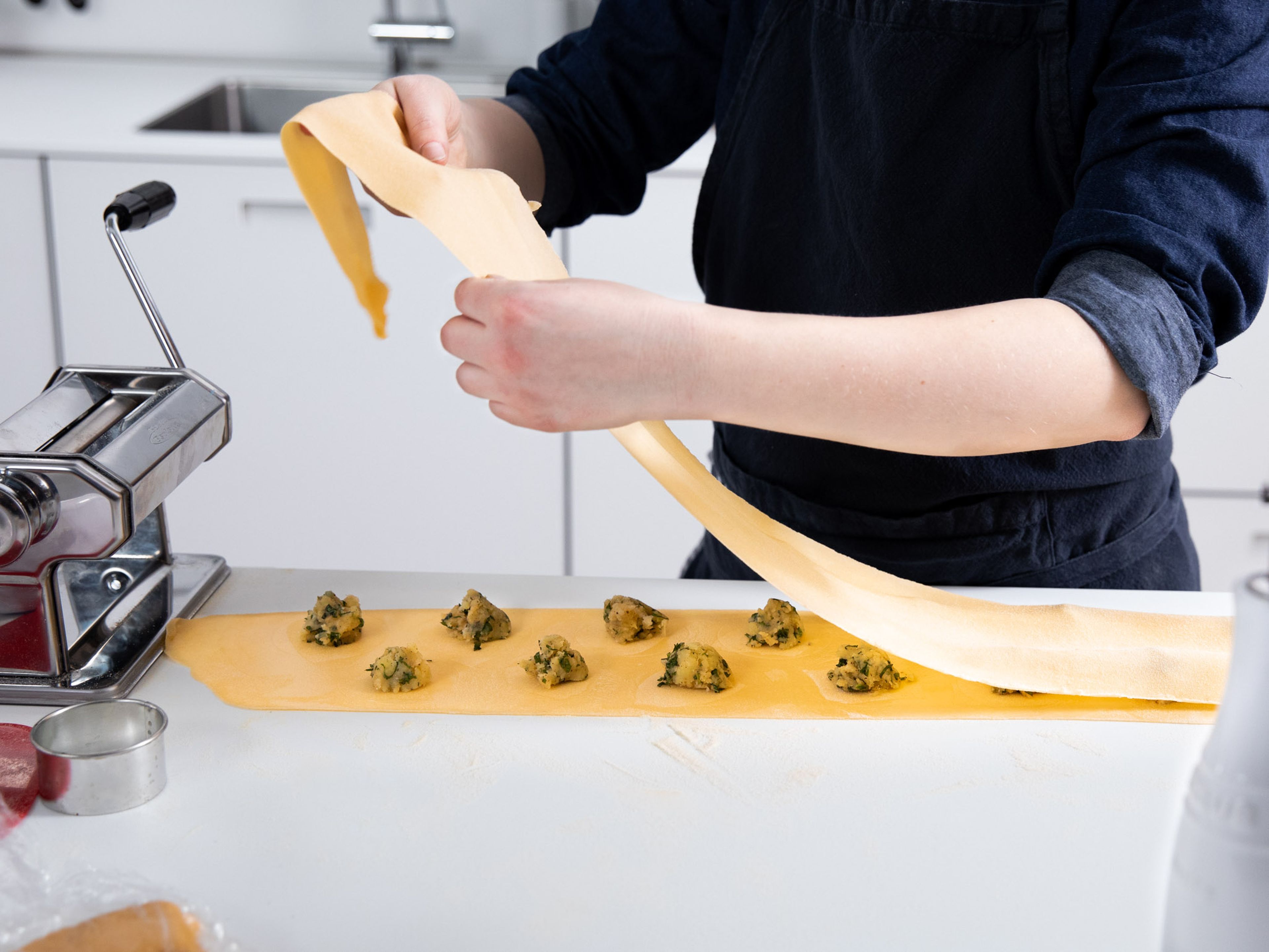 Quarter pasta dough and use a pasta machine to roll out the dough. Stamp out discs of dough for the ravioli with a round cookie cutter. Add a spoonful of potato and mint filling to one disc and brush the dough with some water. Place a second disc of dough on top and press around the edges to seal. Repeat the process with remaining dough and filling.