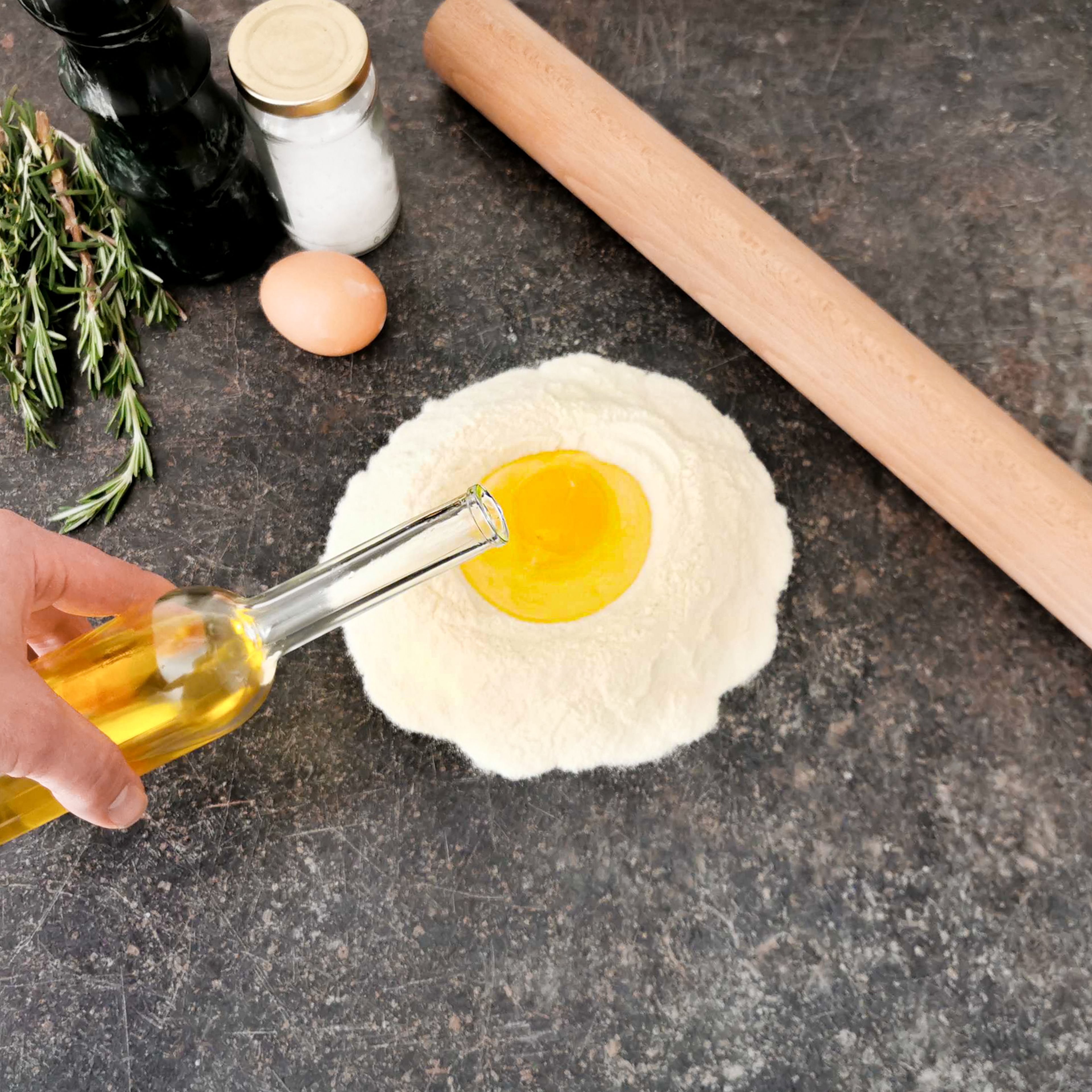 Den Hartweizengrieß und das Salz auf die Arbeitsfläche geben. Eine Kuhle bilden und die Eier darin aufschlagen. Wasser und Olivenöl ebenfalls dazugeben. Die Zutaten mit den Händen zu einem Teig verarbeiten und anschließend zu einer Kugel formen. Den Teig in eine Schüssel geben und mit Frischhaltefolie zugedeckt im Kühlschrank für 30 Min. ruhen lassen.