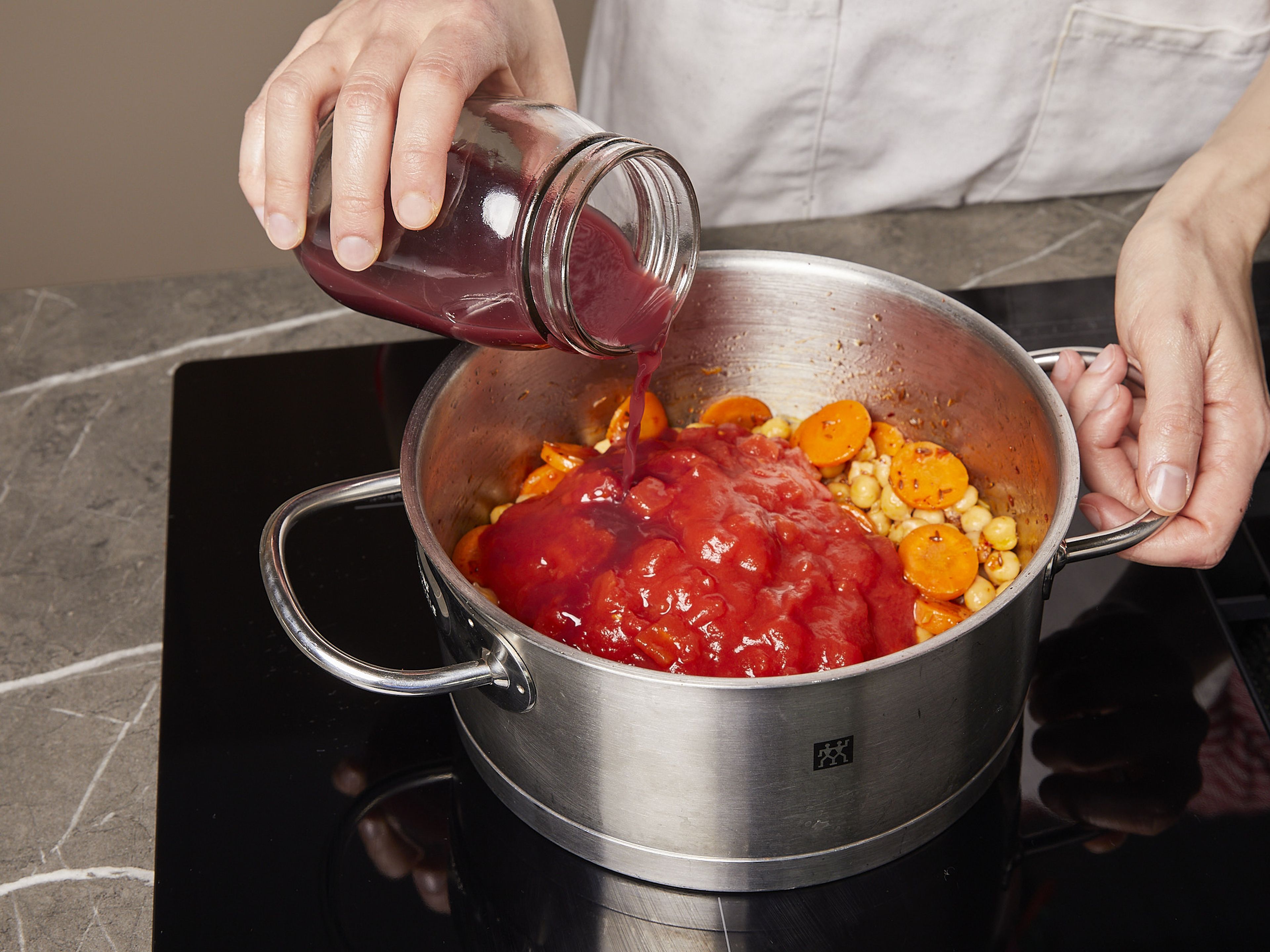 Die Kichererbsen abspülen und abtropfen lassen. Knoblauch hacken und Zwiebel würfeln. Karotte in dicke runde Scheiben schneiden. Olivenöl in einem Topf erhitzen und Zwiebeln und Knoblauch mit Karotten, Chiliflocken und Kreuzkümmelsamen anbraten. Kichererbsen, stückige Tomaten, Zucker und Granatapfelsaft hinzugeben. Mit Salz würzen und bei starker Hitze unter gelegentlichem Rühren ca. 15 Min. köcheln lassen.