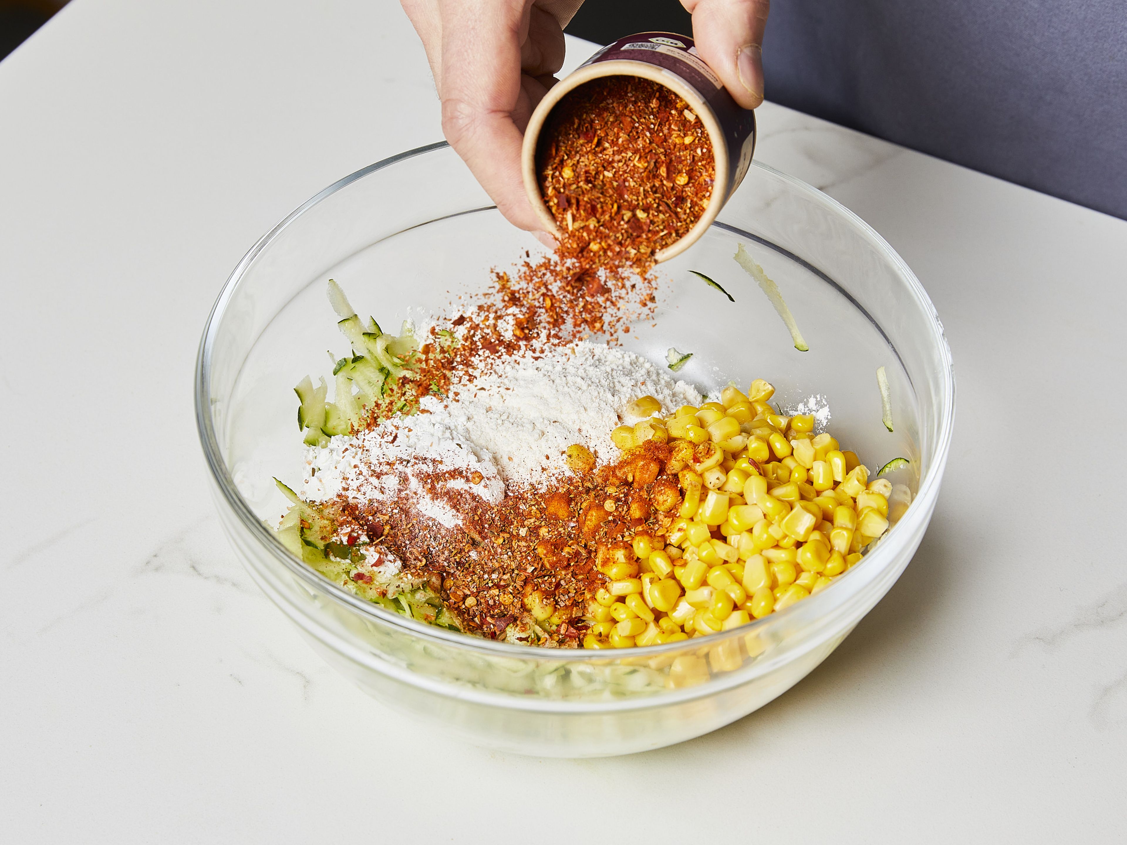 Add drained corn kernels to the bowl with the grated zucchini together with the liquid. Fold in the flour, cornstarch, and our VIVA LA SPICE seasoning. Mix well until a batter forms.
