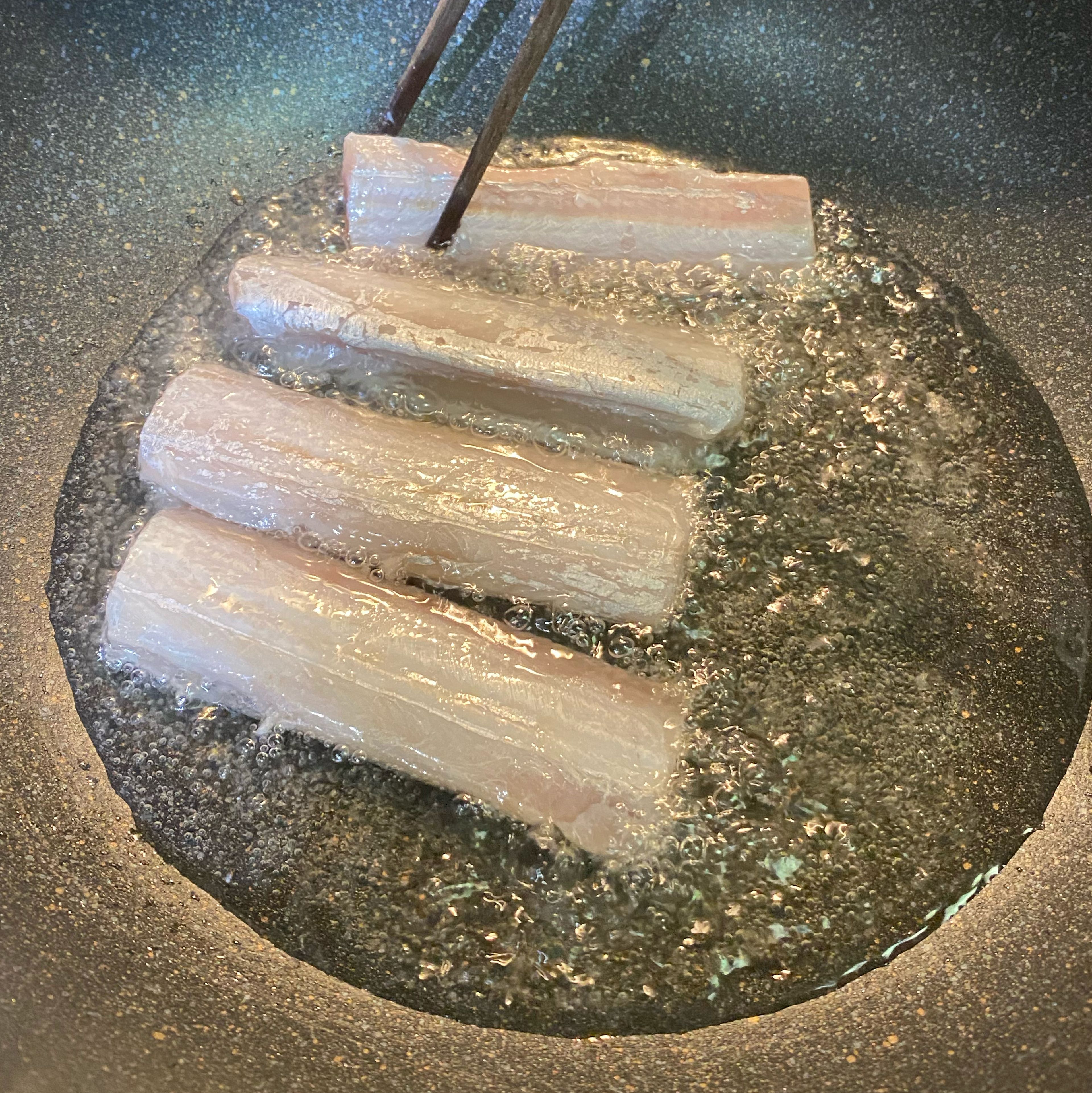 When the oil forms bubbles when you stick the chopsticks in it, it’s ready for frying. Turn heat down to medium. Carefully add each fish into the pan; don’t crowd them. Use a pan cover if oil is splattering out.