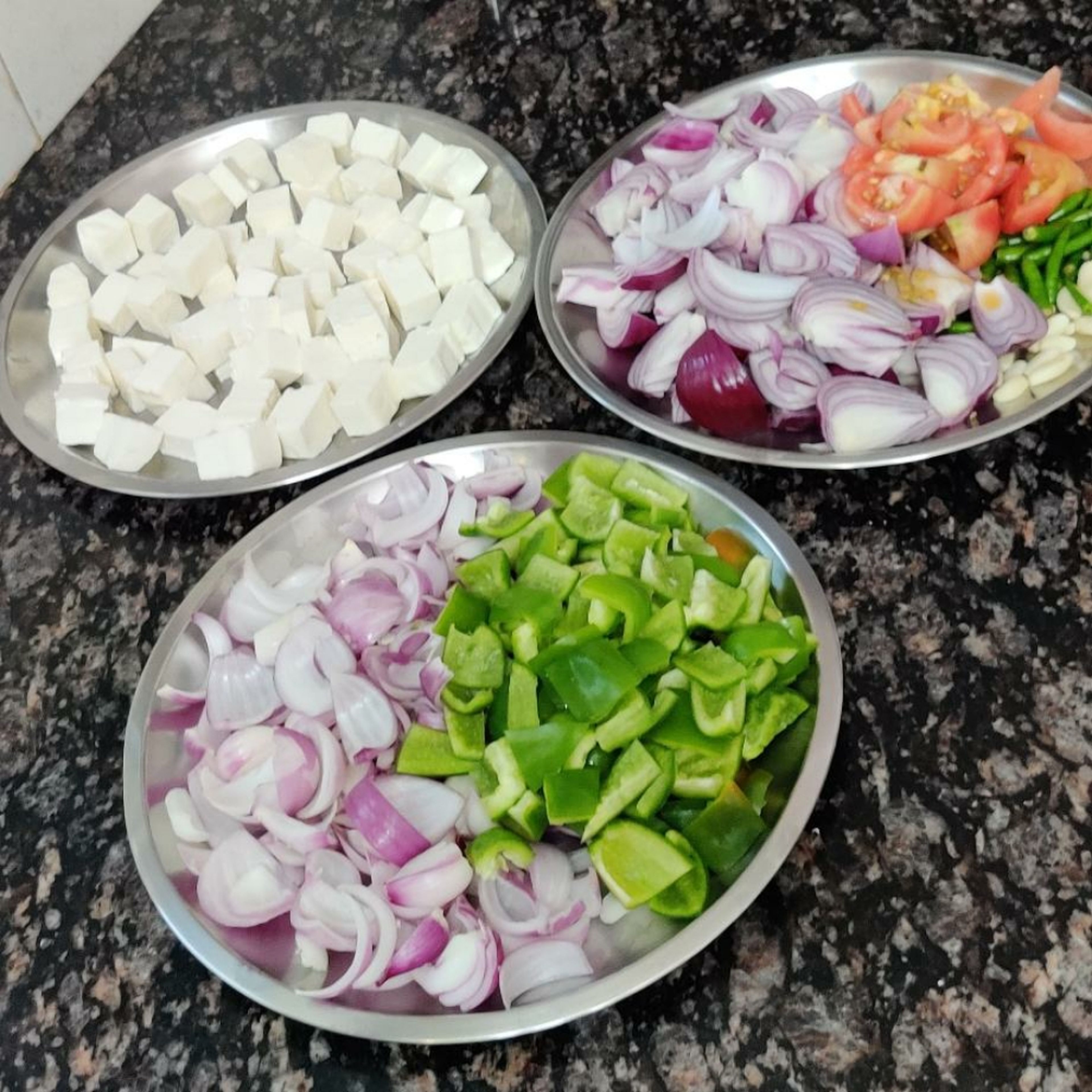Cut onions, tomatoes, green chillies, garlic, capsicum and paneer.