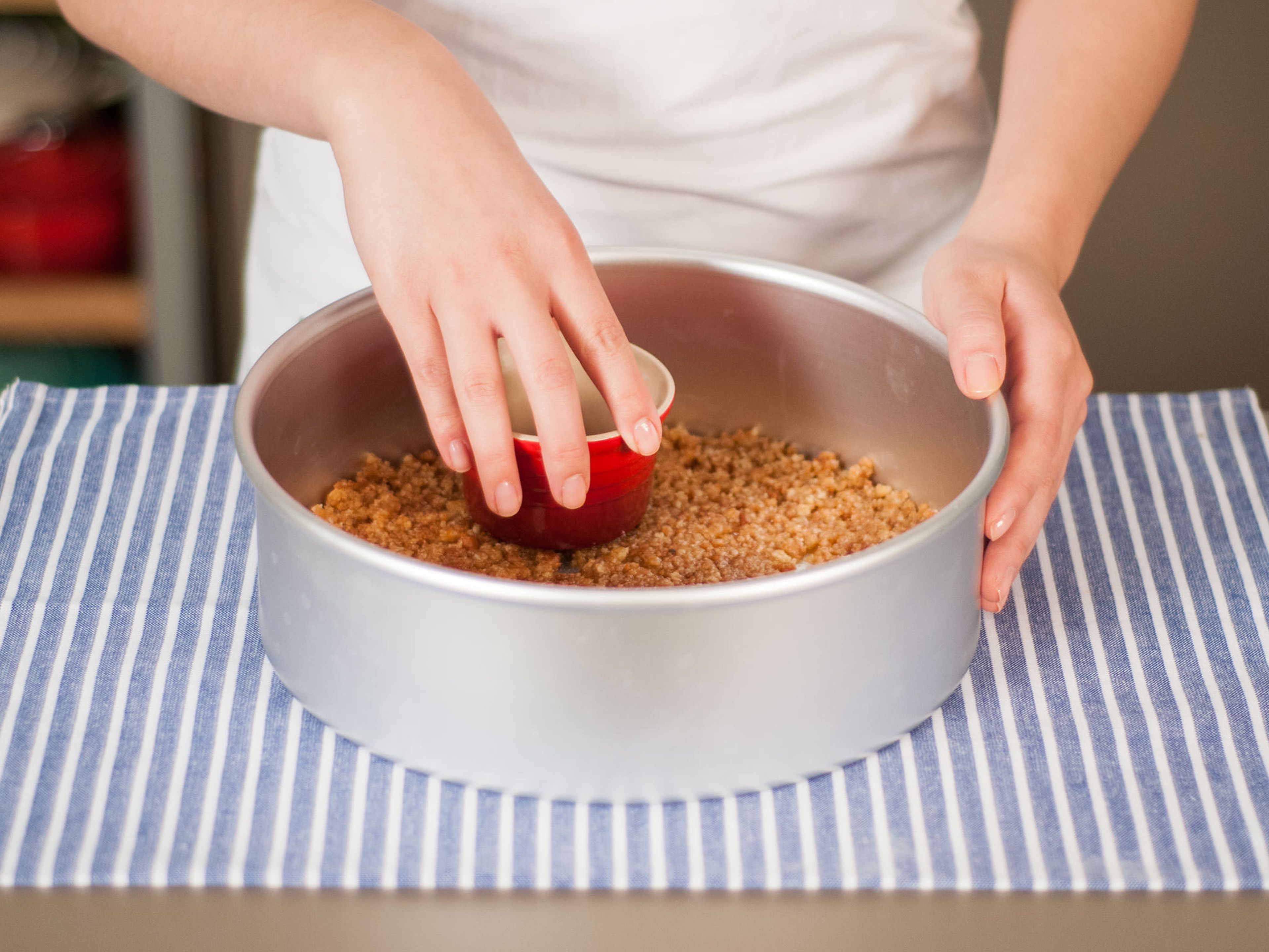Add cookie crumb mixture to a round baking form and press firmly into bottom of baking form.