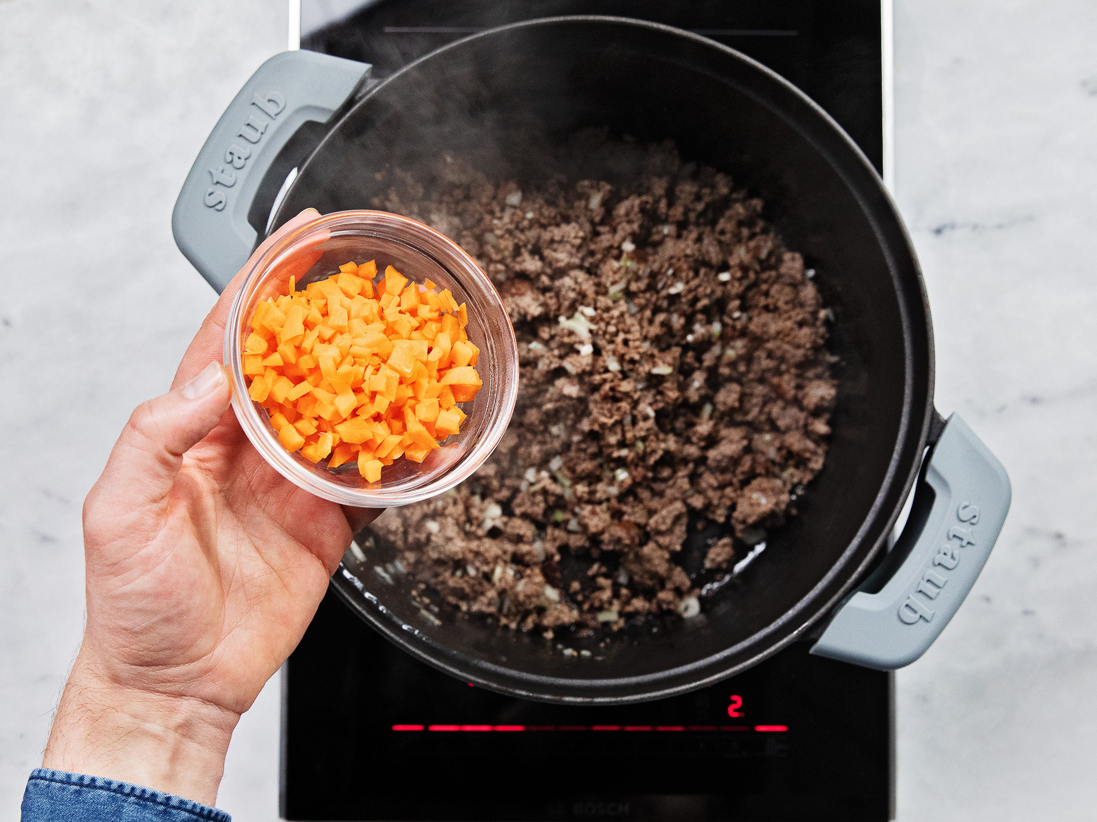 Add oil to a heavy-bottomed pot over medium-high heat. Add beef and let brown. Then add garlic, onion, carrot, and celery. Season with salt and pepper and let cook until onions are translucent.