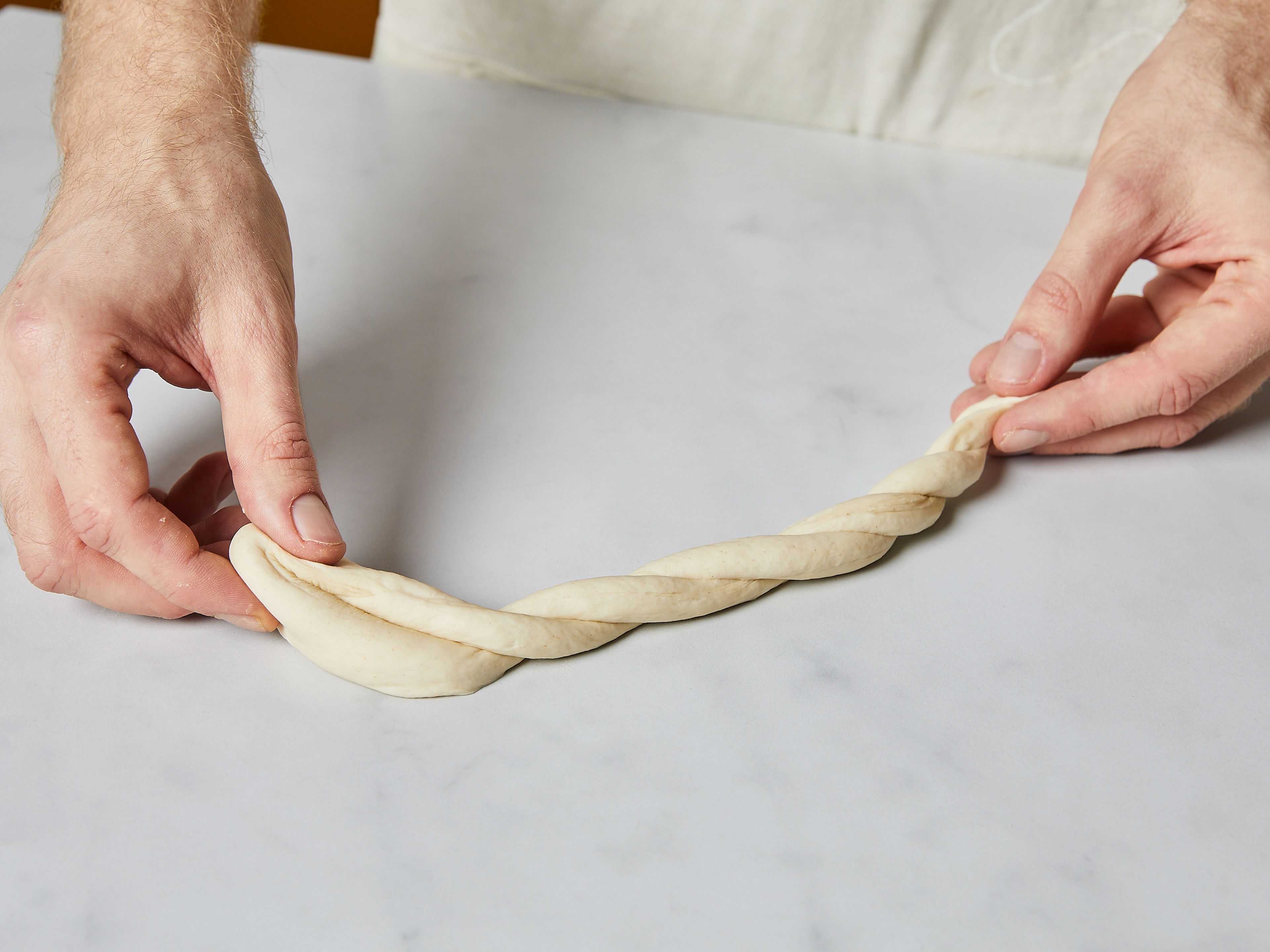 Preheat the oven to 250°C/480°F. Work with two dough balls at a time and roll each ball into a 30 cm long rope. Braid the two ropes together, and pinch the ends together to create a ring. Lightly roll out the ring with your hand, creating a 15-20 cm large diameter.