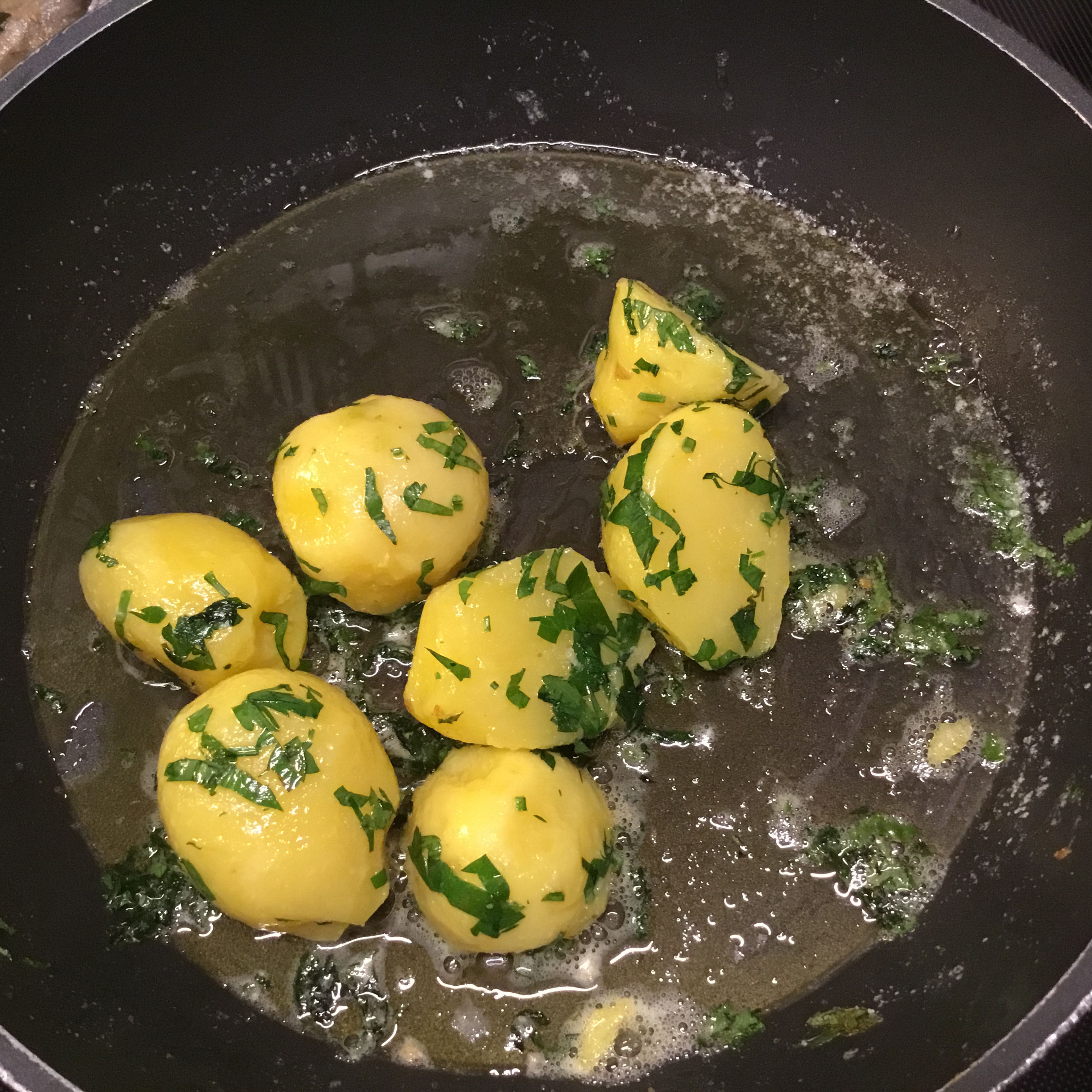 Kartoffeln kochen, schälen, Petersilie schneiden, und eine Pfanne mit geschmolzener Butter vorbereiten.