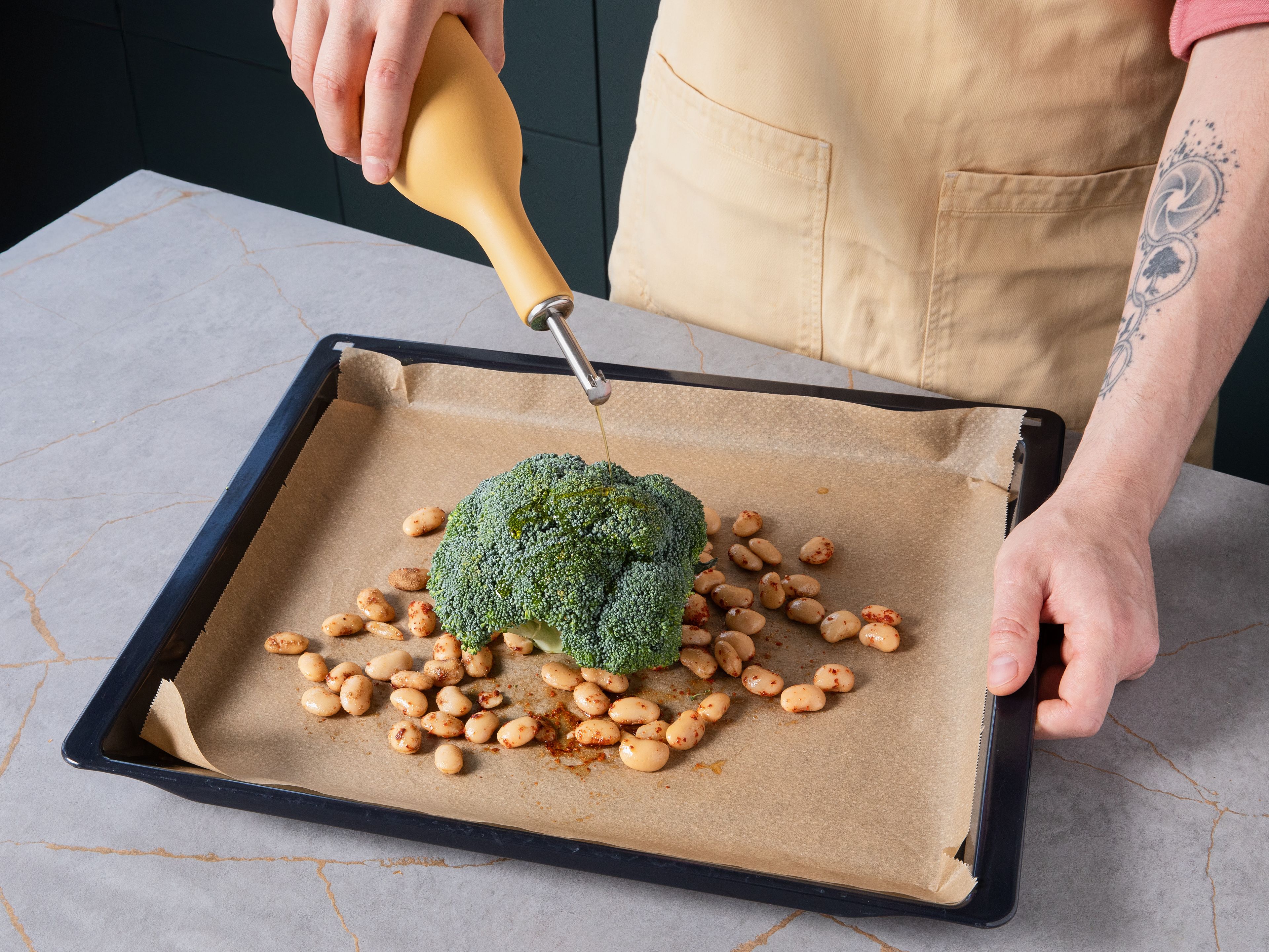 Preheat oven to 200 °C/390 °F (fan). Trim stem of the broccoli. In a bowl, toss half the cooked beans with half the olive oil, ground coriander, chili flakes, salt, and pepper. Place broccoli on a baking sheet, drizzle with remaining olive oil, and rub with salt. Scatter the seasoned beans around it and roast everything for approx. 25–30 min., until the broccoli is tender and browned, and the beans are crisp.