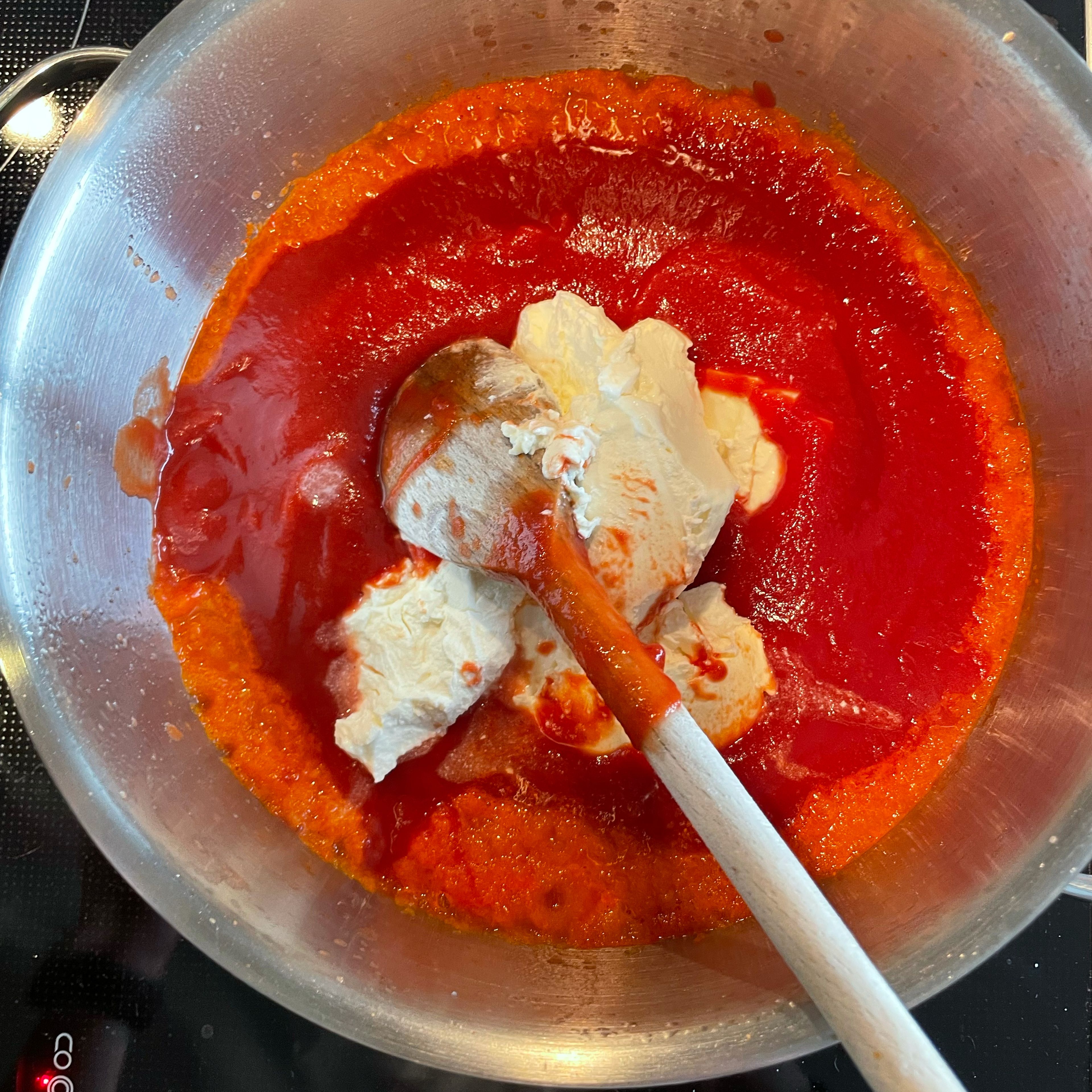 Passierte Tomaten und Frischkäse zugeben, unterrühren und aufkochen lassen. Mit Salz und Pfeffer abschmecken.