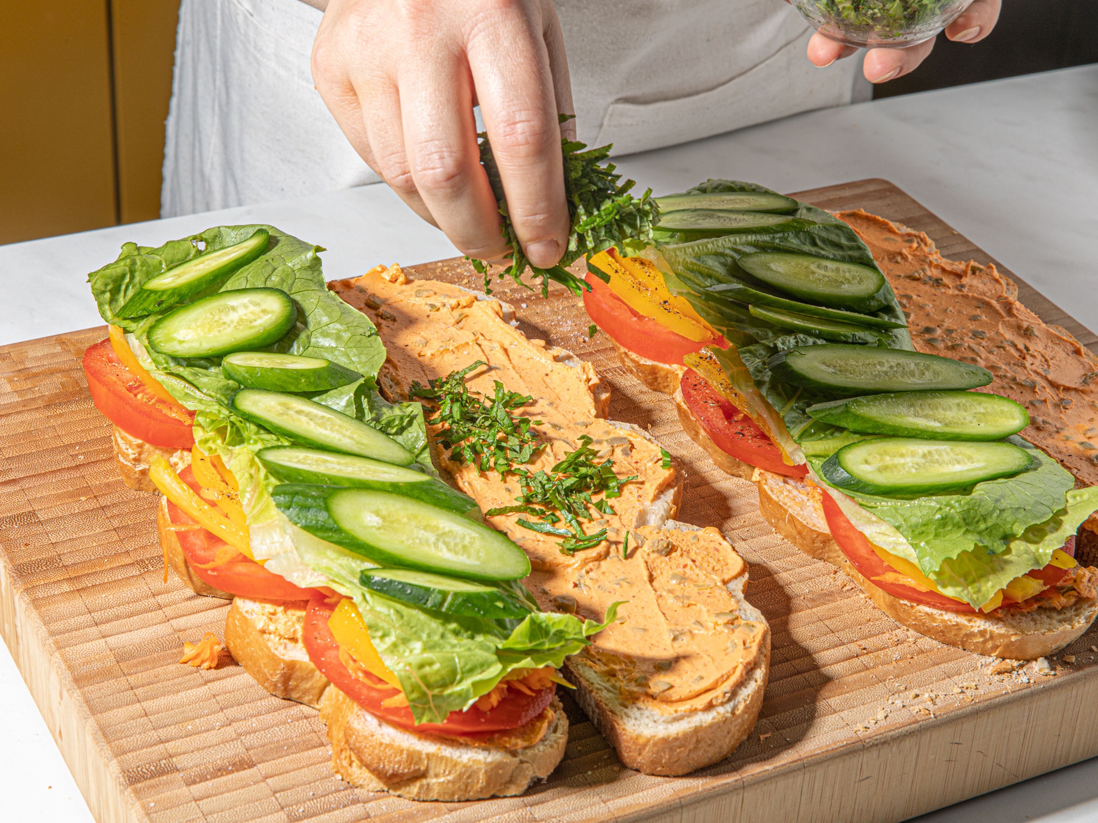 To assemble the sandwiches, spread cream cheese evenly over one side of each piece of bread. Stack the tomato, salt, pepper, lettuce, bell pepper, cucumber, herbs, and carrots, then cover with the extra slices of bread, cream cheese side down. Press well with your hands to squish the sandwich together a bit, then slice if desired and serve. Enjoy!