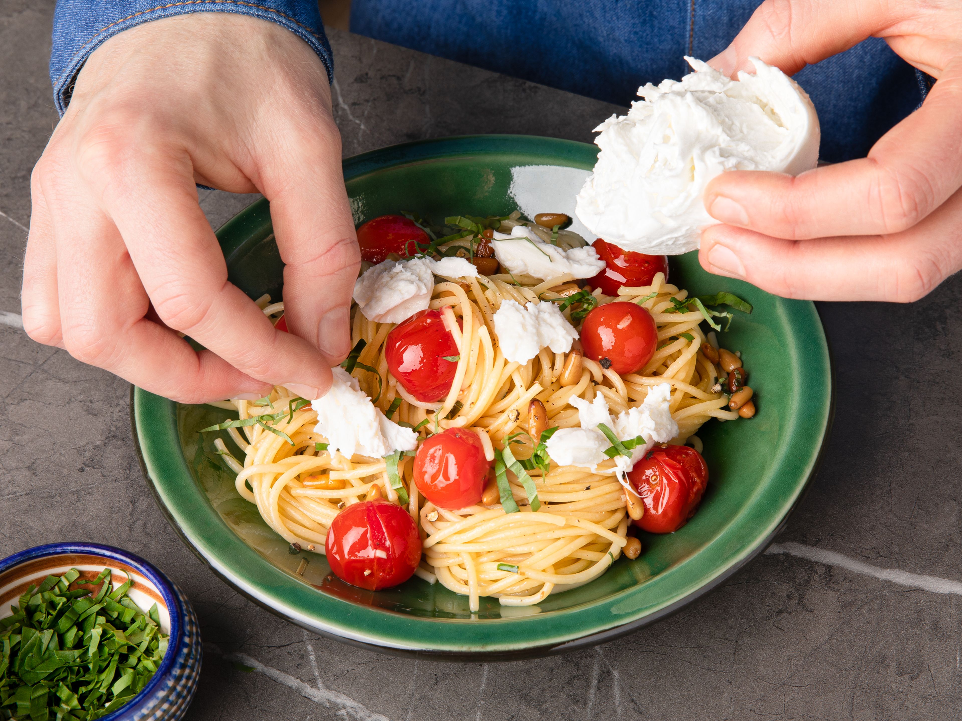 Spaghetti abgießen und die Tomaten aus dem Backofen nehmen. Restliche Butter in einer Pfanne über mittlerer Hitze schmelzen lassen und den gehackten Knoblauch ca. 1 Min. anbraten. Spaghetti und Tomaten dazugeben und vermengen. Mit Salz und Pfeffer abschmecken. Mozzarellakäse mit den Händen in kleine Stücke zerreißen und über den Spaghetti verteilen. Zum Schluss Pinienkerne und Basilikum darüber verteilen. Guten Appetit!