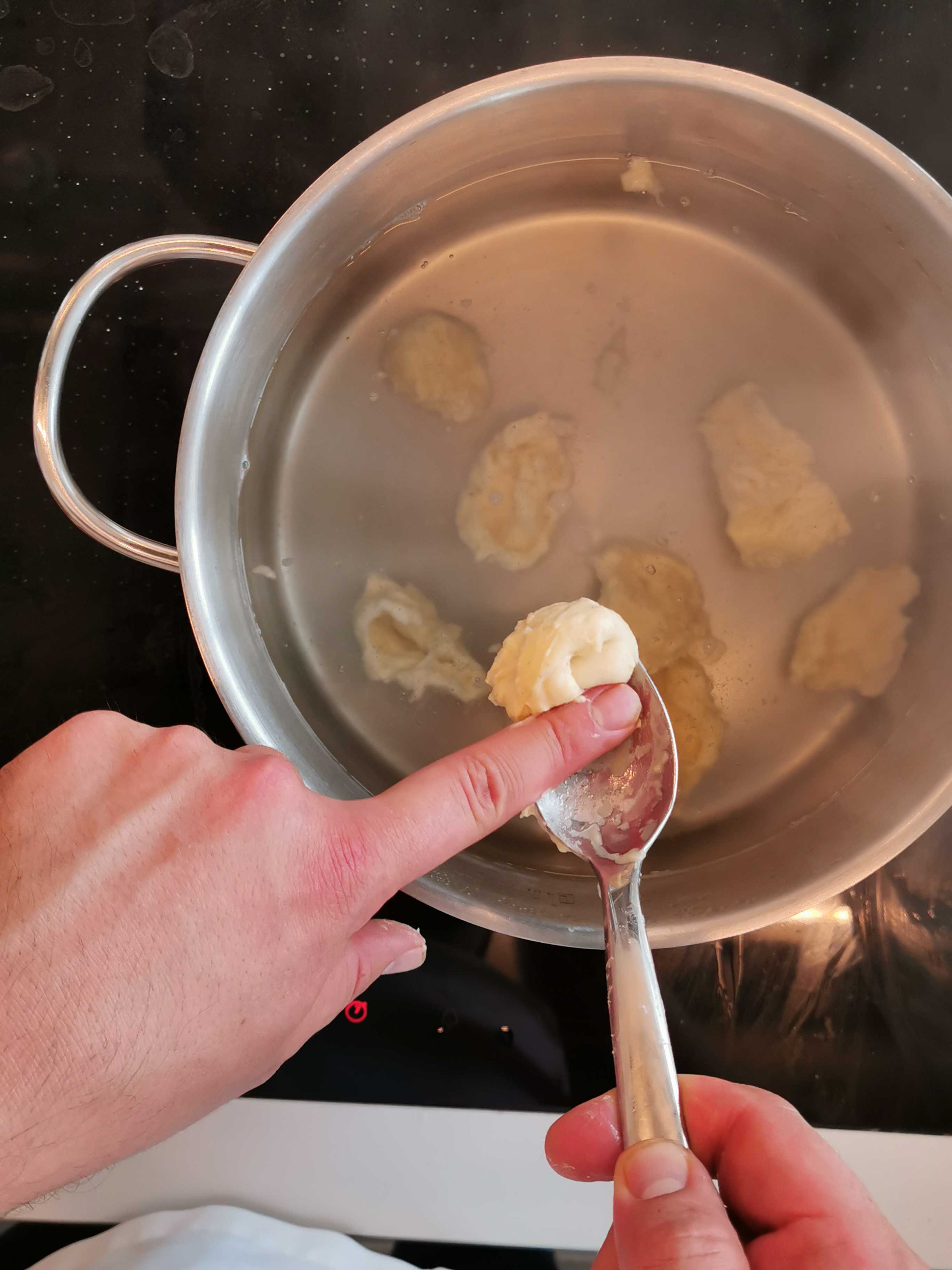 Vom Teig mit einem Esslöffel Teigteile abstechen, in das kochende Wasser geben und 5 Minuten ziehen lassen. Kartoffeln schälen, waschen, in Stifte schneiden und in Salzwasser garen.