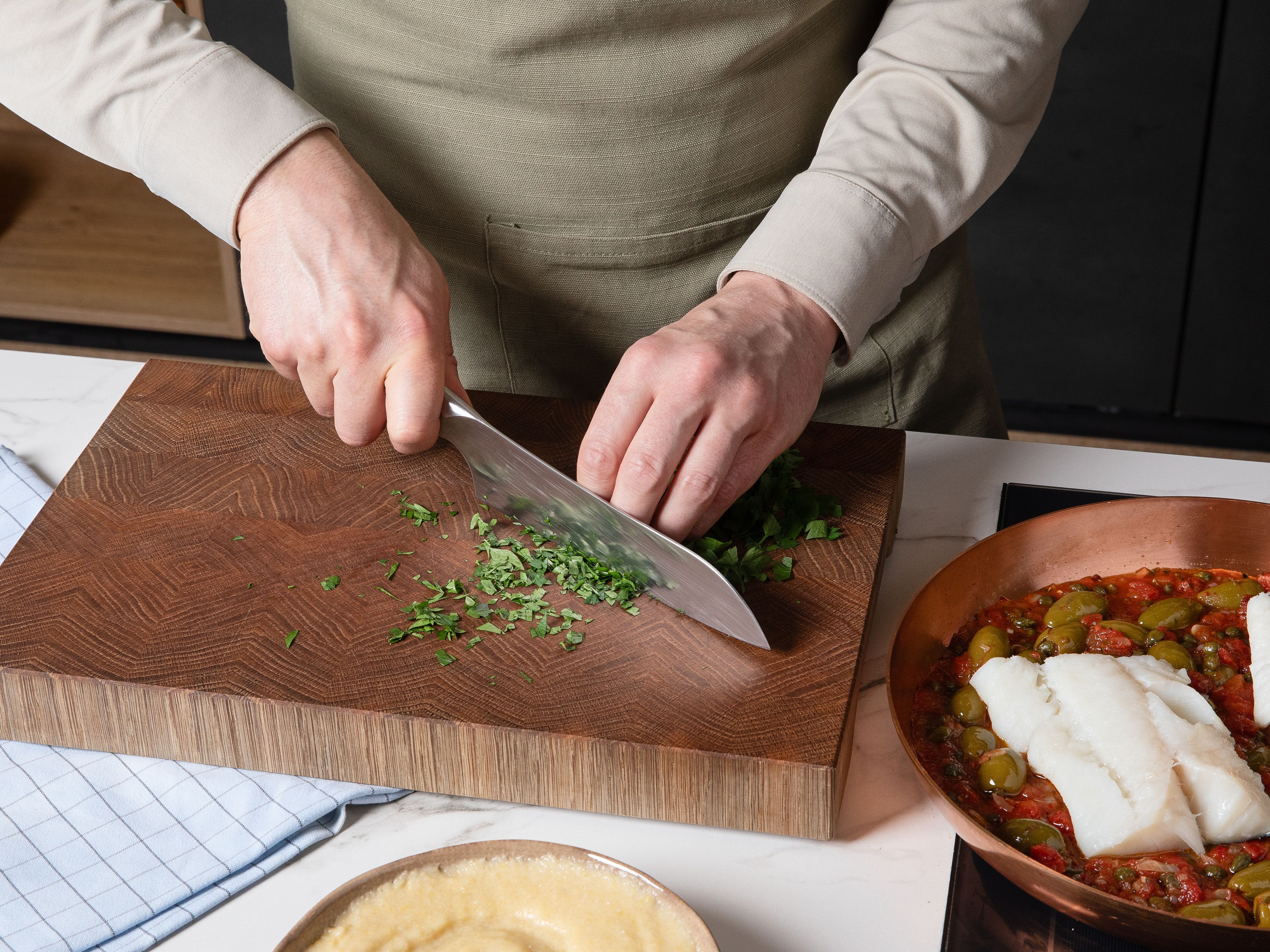 Petersilie fein hacken. Die cremige Polenta auf Teller verteilen, den geschmorten Fisch mit der würzigen Puttanesca-Sauce darauf anrichten und mit gehackter Petersilie garnieren. Sofort genießen!