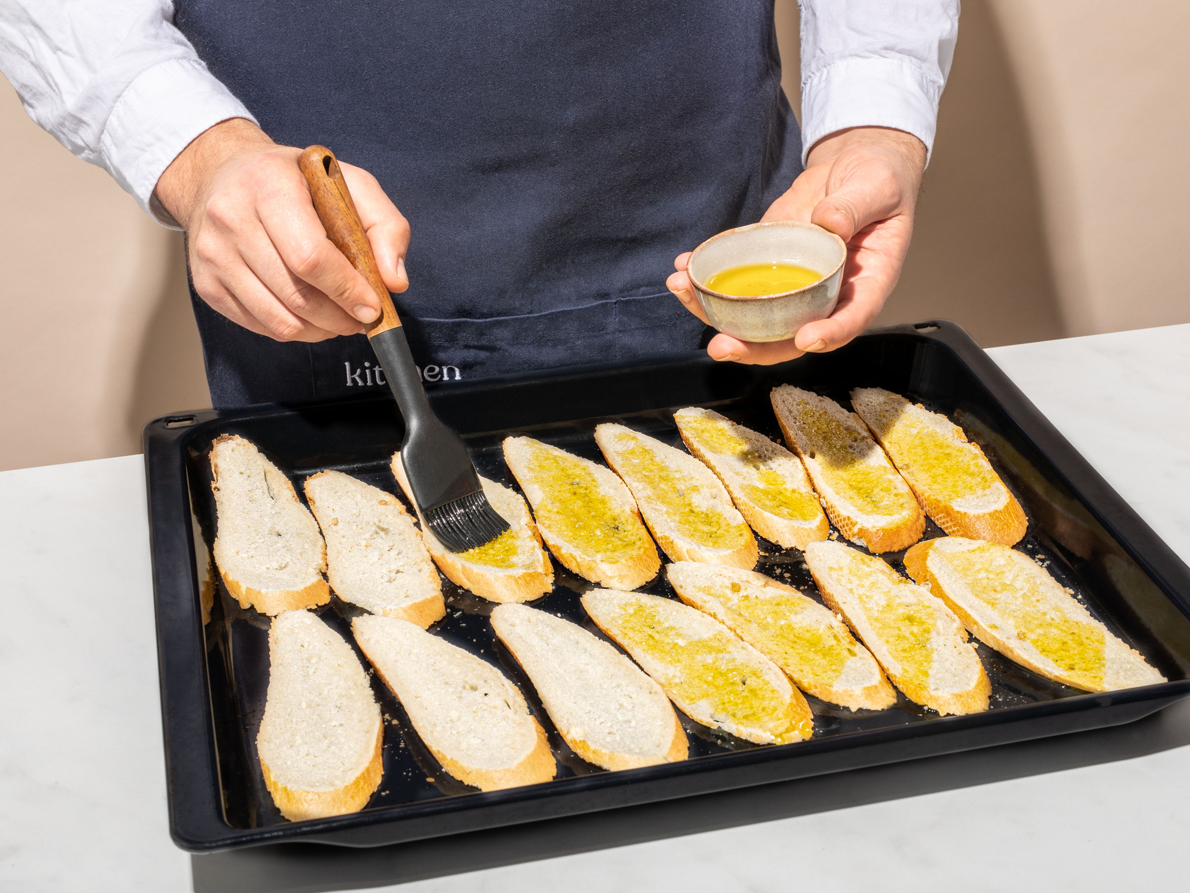 Das Baguette in Scheiben schneiden, mit etwas Olivenöl bestreichen und bei 180 Grad im Ofen für etwa 5 Min. backen.