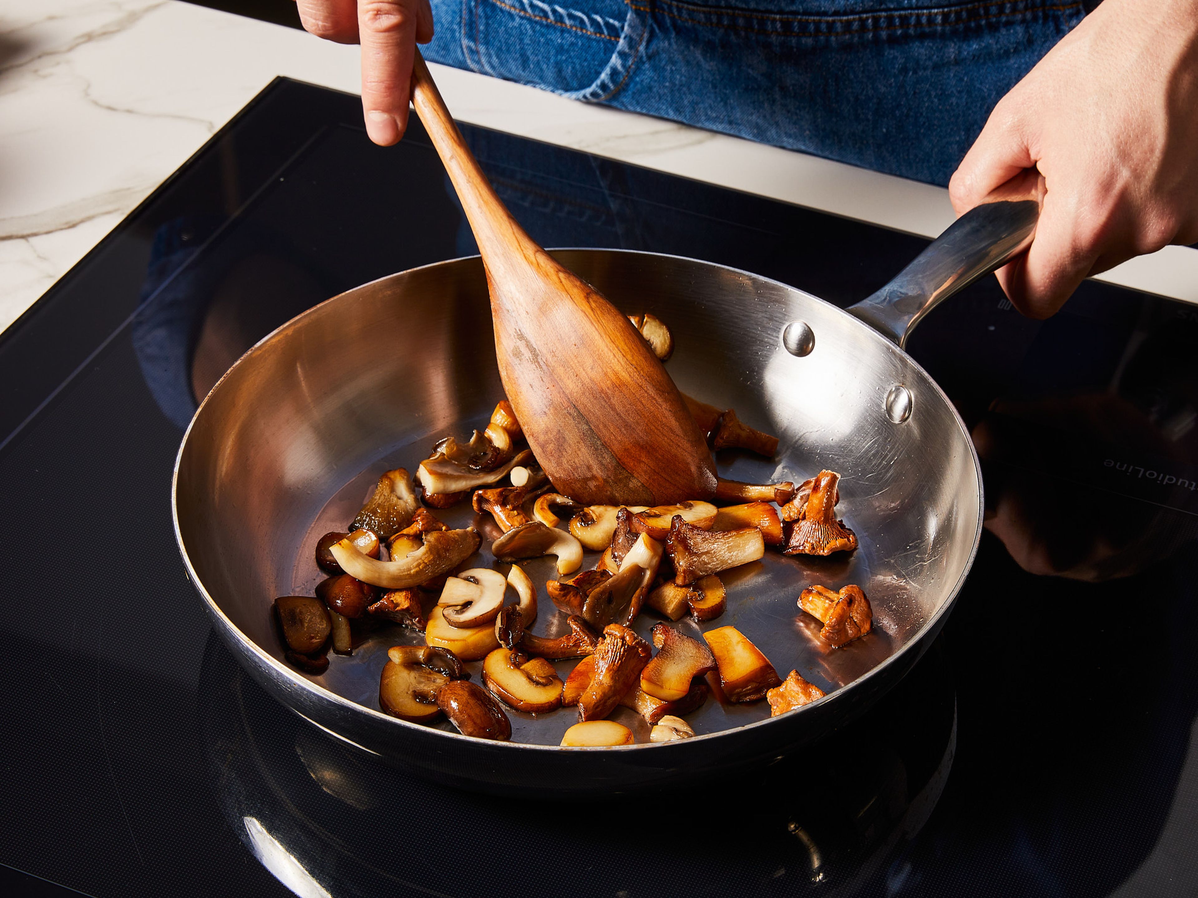 In der Zwischenzeit die Pilze putzen und klein schneiden. Restliches Öl in einer Pfanne erhitzen und die Pilze darin bei mittlerer Hitze anbraten, bis sie leicht gebräunt sind. Die Pilze mit Salz und Pfeffer würzen und einige zum Garnieren beiseite stellen. Die restlichen Pilze zu den Zwiebeln und dem Knoblauch in den Topf geben und gut umrühren.