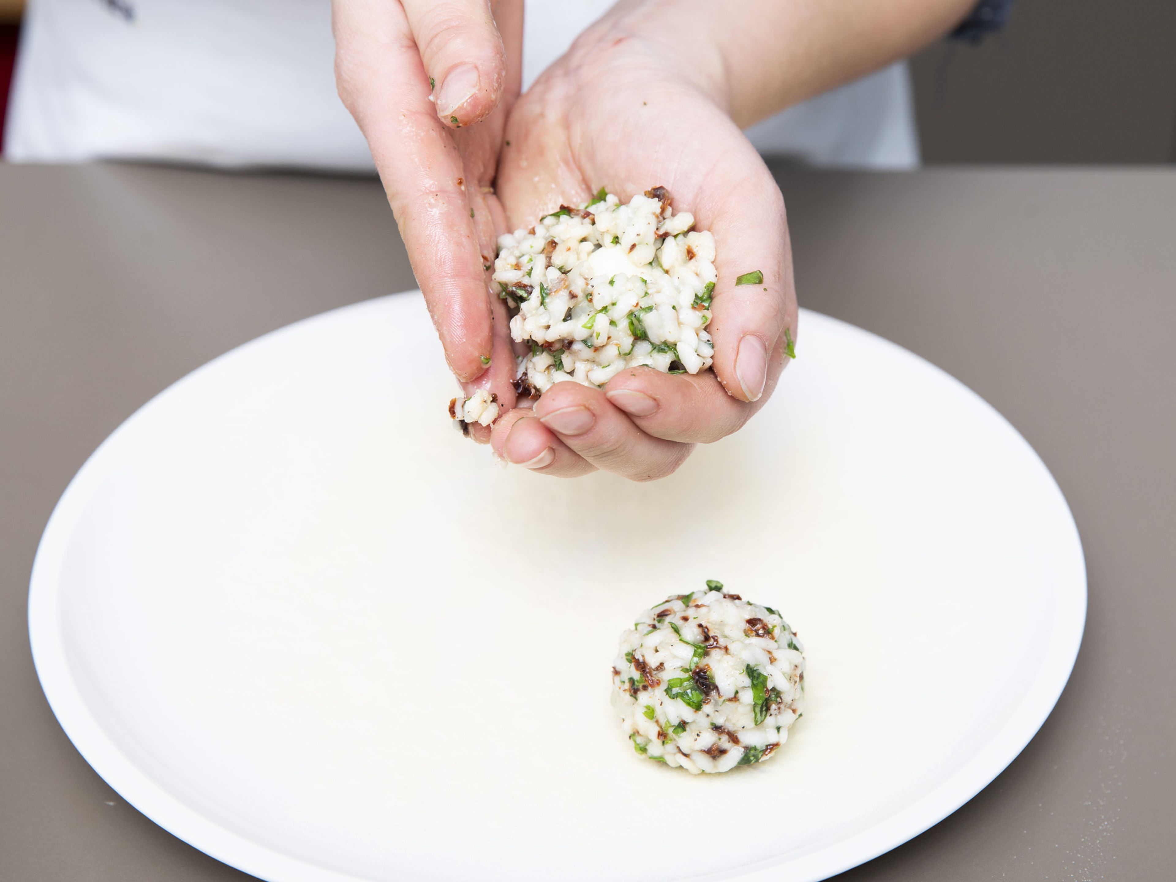 Divide mozzarella cheese into smaller pieces. With damp hands, form some of the risotto mixture around each piece of mozzarella and roll into equal-sized balls. If you want to make the breading easier, refrigerate the arancini for approx. 30 min.