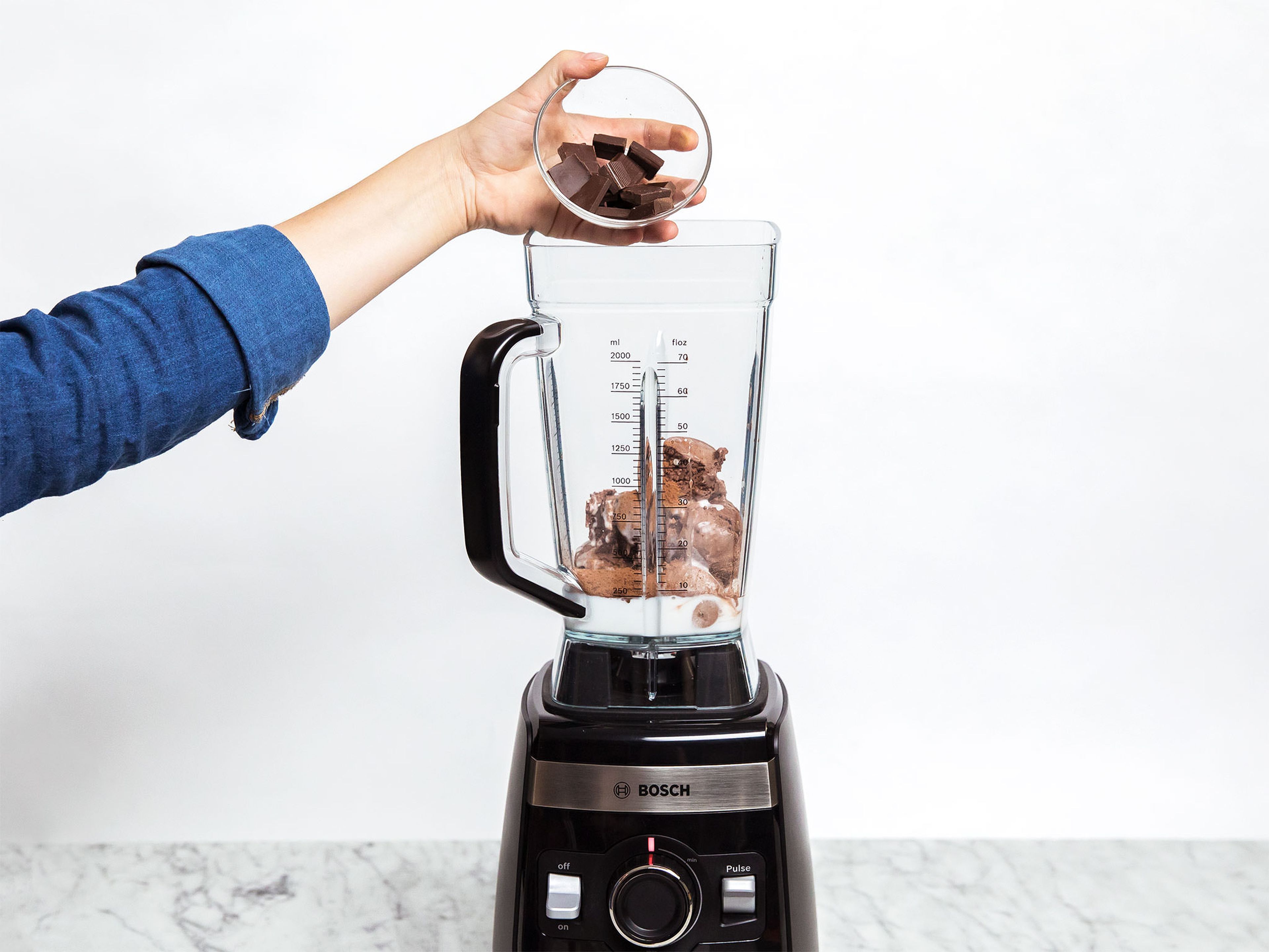 Schokoladeneis, Kokosmilch, Backkakao und Zartbitterschokolade in den Standmixer geben und mit der Shake-Funktion des Mixers cremig mixen.