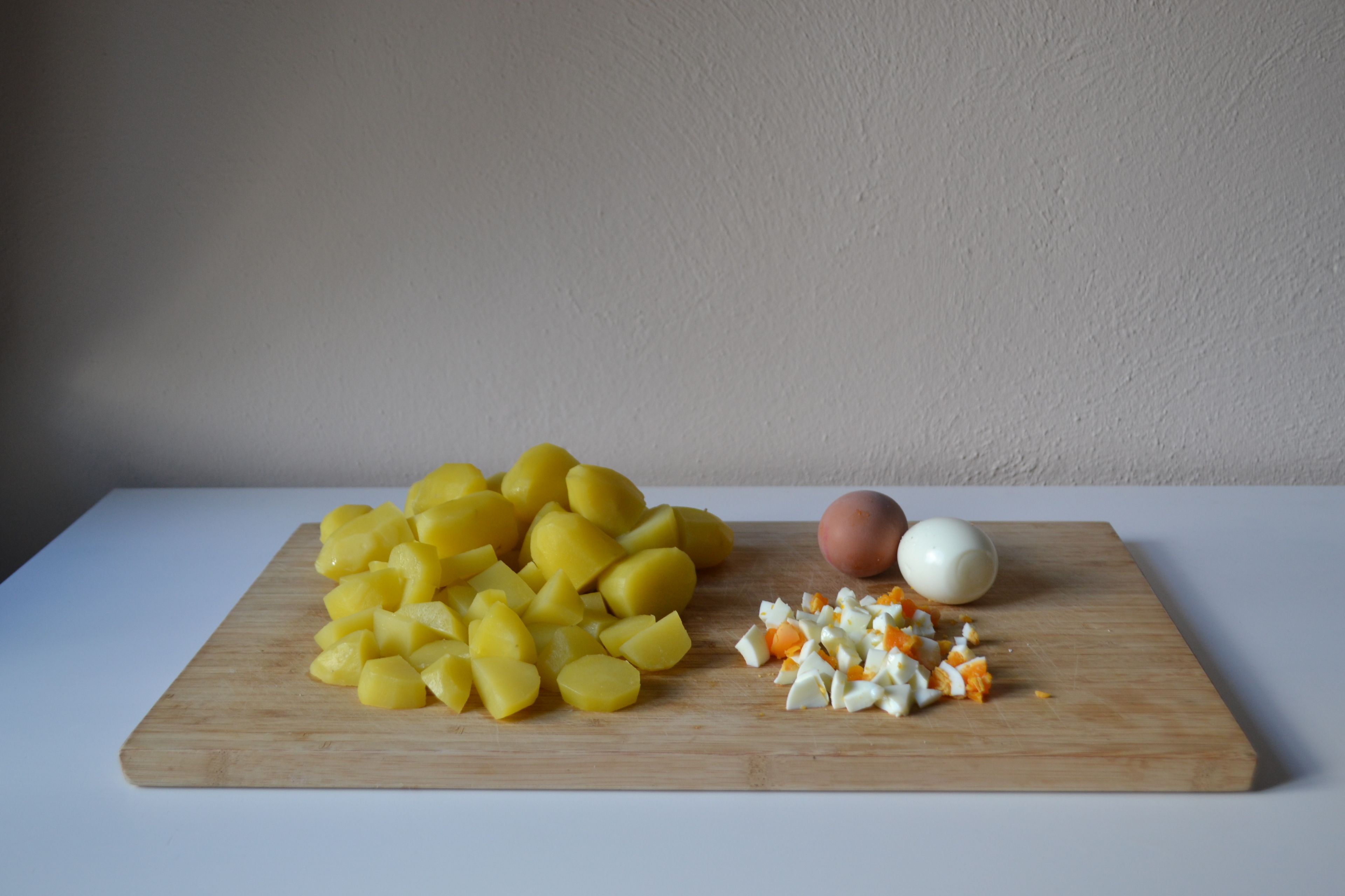 Die kalten Eier schälen und in kleine Stücke schneiden. Die Kartoffeln nach Belieben in größere Stücke schneiden. Beides zusammen mit den Gewürzgurken- und Apfelstücken in eine Schüssel geben.