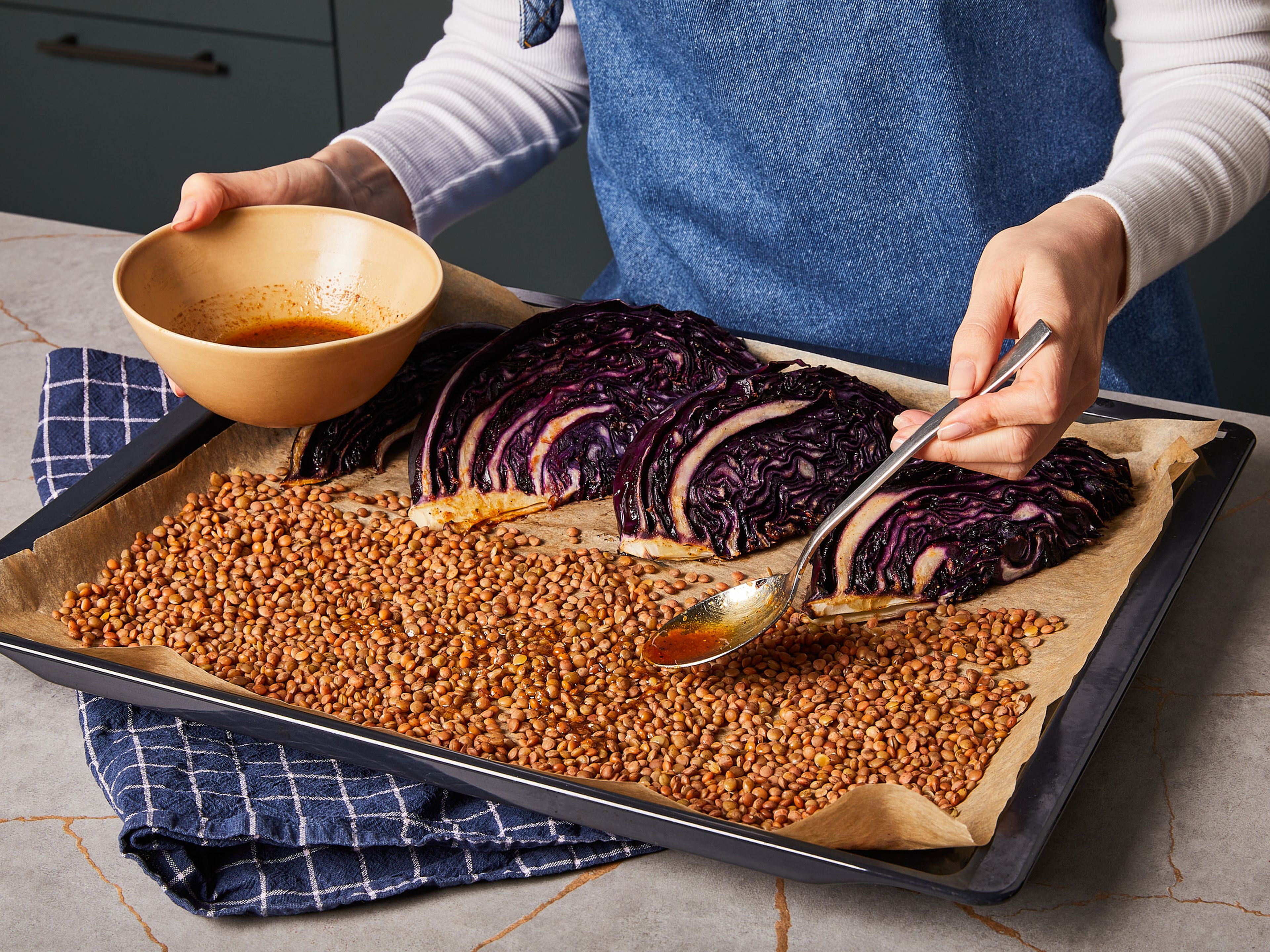 Die Rotkohl-Wedges auf der einen Hälfte des Backblech platzieren und von beiden Seiten mit einem Drittel der Marinade bestreichen. Backblech in den Ofen geben und insgesamt ca. 40 Min. backen. Nach ca. 20 Min. den Kohl wenden und die gekochten Linsen ebenso aufs Blech geben. Linsen mit einem weiteren Drittel der Marinade beträufeln, gut vermischen und in einer dünnen Lage auf dem Blech verteilen und bis zum Ende der Backzeit mit backen, bis sie knusprig sind.