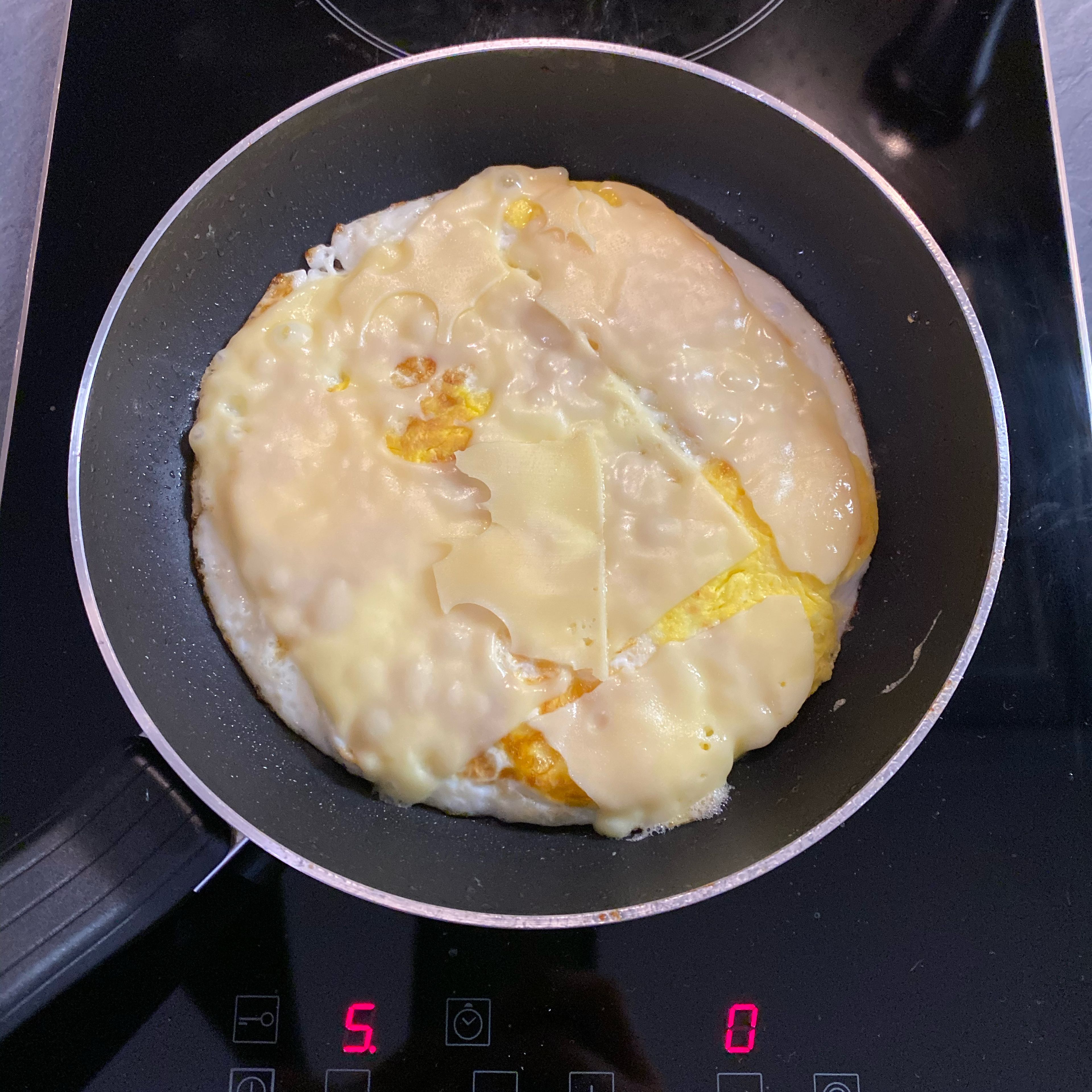 Nun die Eier aufschlagen und als Spiegeleier mit ein wenig Öl und gut gesalzt zubereiten. Den Käse auf die Eier legen, kurz bevor sie fertig sind, damit er noch schön schmilzt.