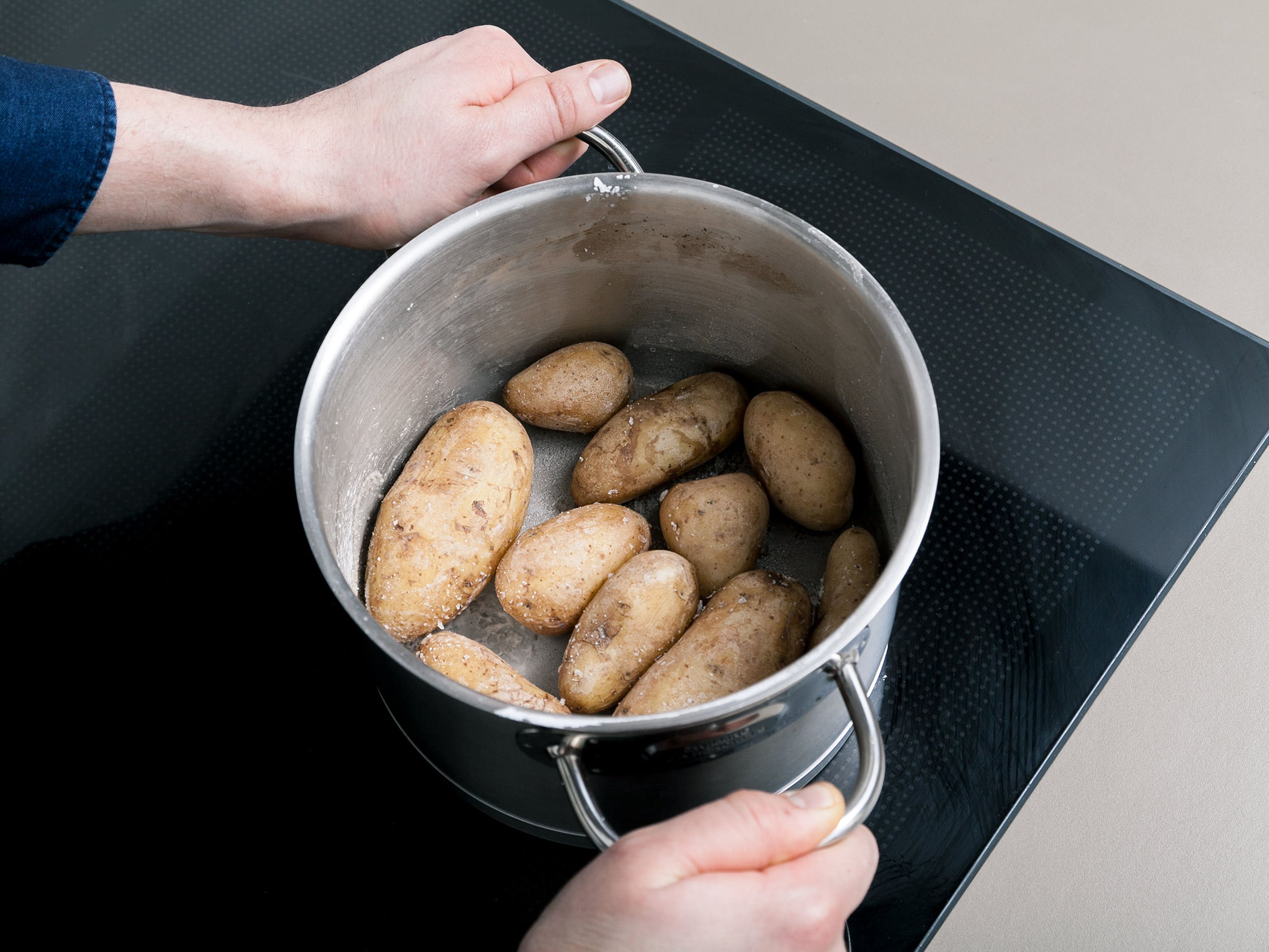 Das Wasser aus dem Topf fast vollständig abgießen, sodass noch ein kleiner Rest bleibt. Die Kartoffeln im Topf ohne Deckel erhitzen, bis das Wasser verdampft. Den Topf dabei ab und zu schwenken. Auf diese Weise bekommen die Kartoffeln ihre typische Salzkruste.